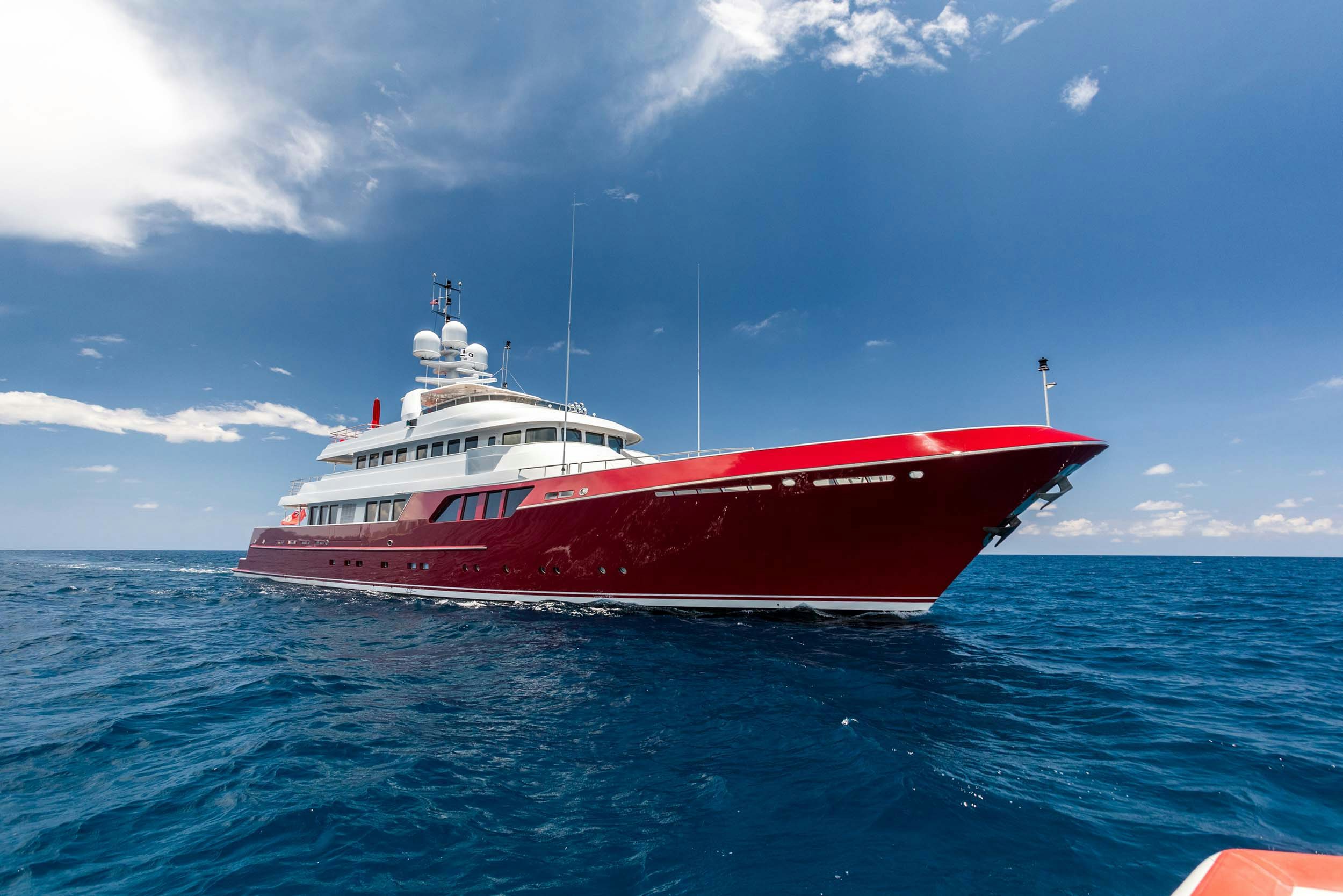 red superyacht profile image on the water with white superstructure