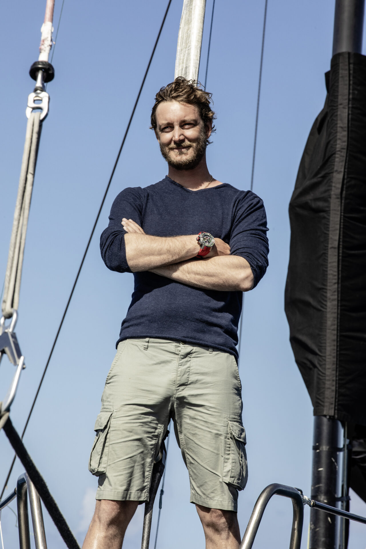 A man standing on the deck of a sailing yacht with a Richard Mille watch