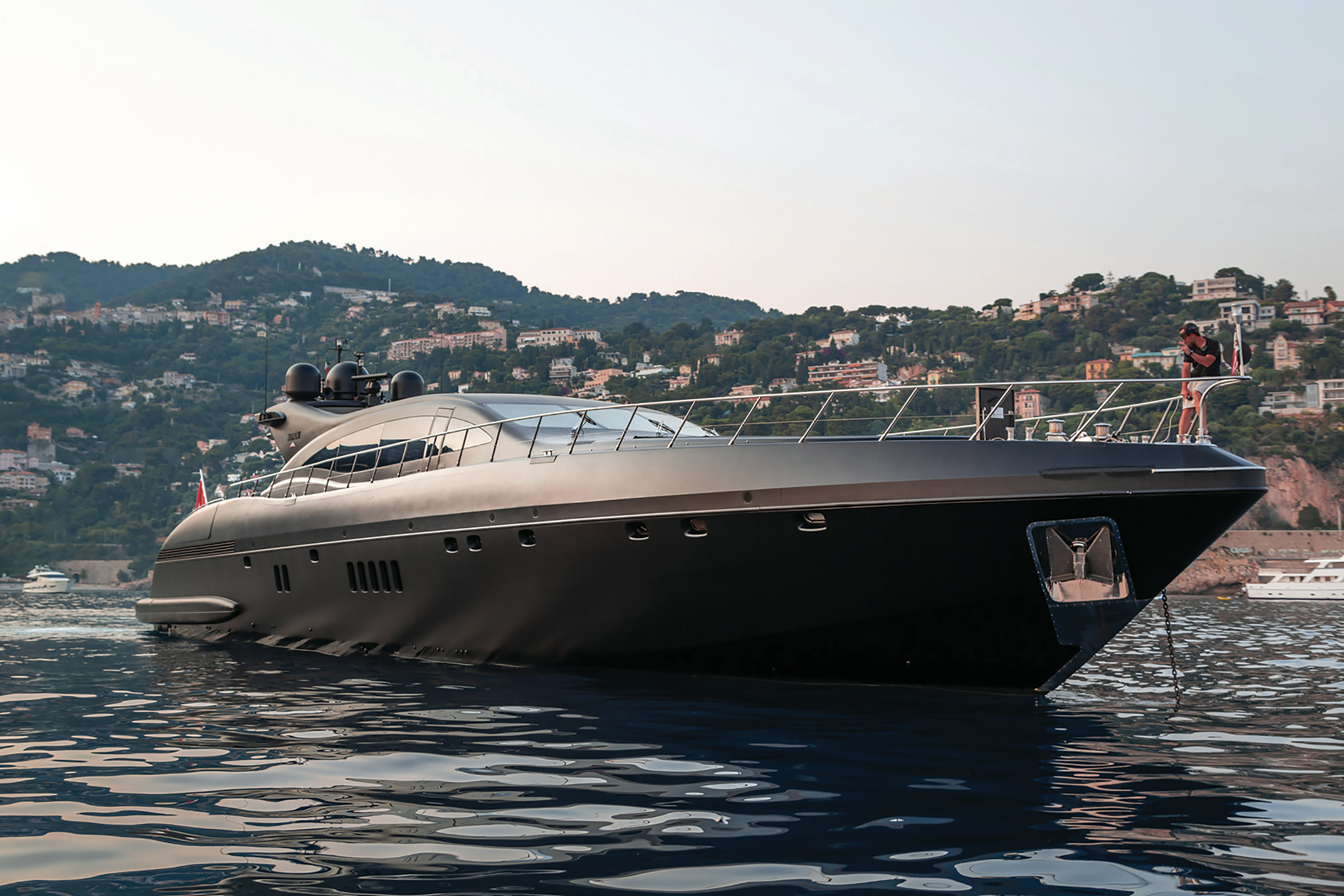 The Mangusta Overmarine yacht moored near a coastal town, exemplifying sleek modern nautical architecture.