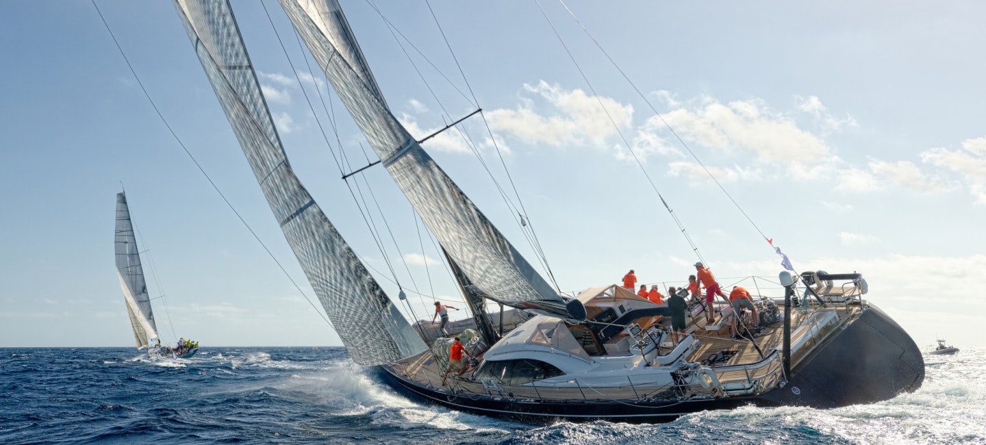 A massive sailing yacht, sails billowing in the wind, speeds through the water during a windy day at the Les Voiles De Saint-Tropez regatta.