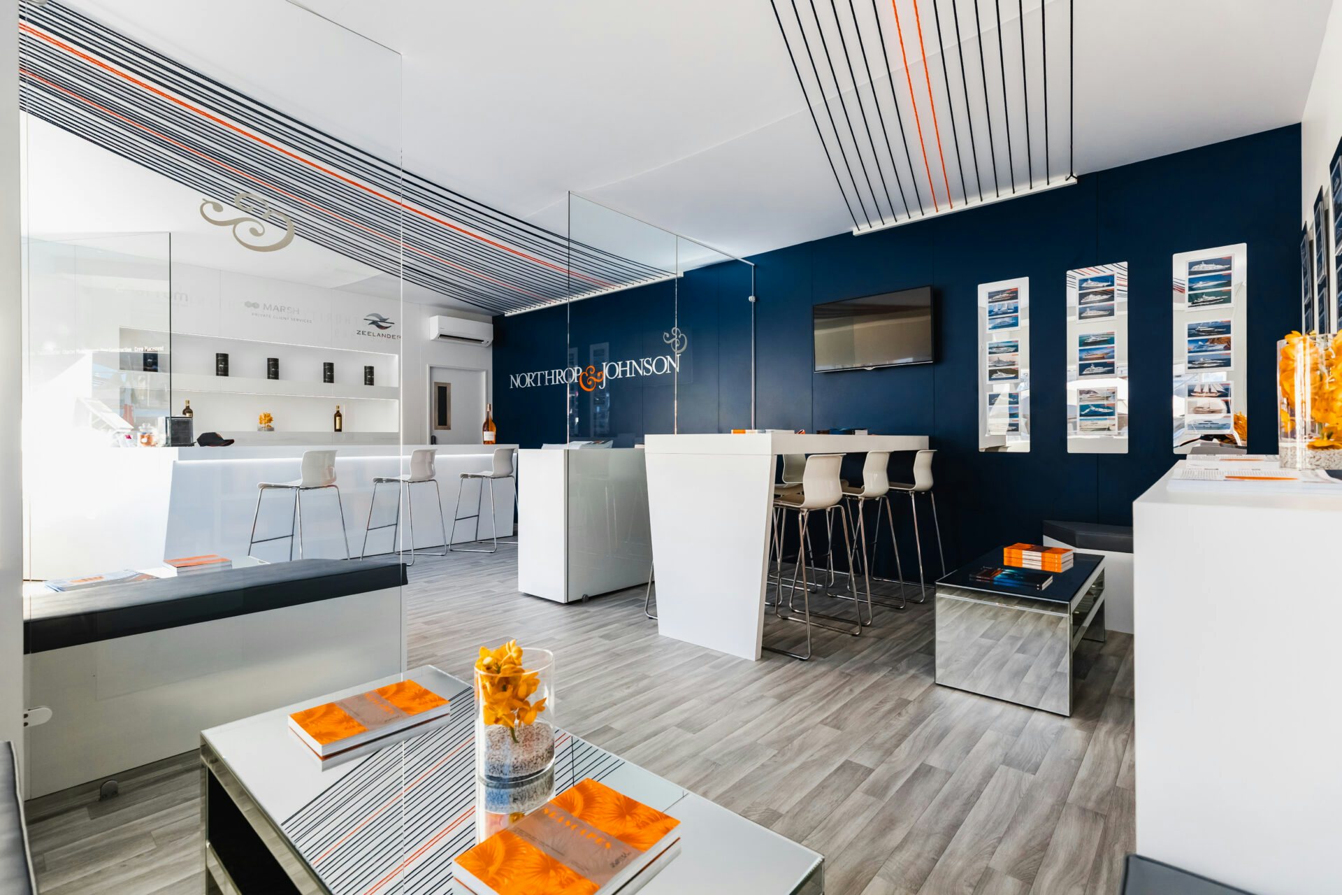 The N&J yacht brokers' booth, adorned with their branded colors of blue, white, and orange, stands out at the prestigious Monaco Yacht Show, offering yachts for charter and yachts for sale