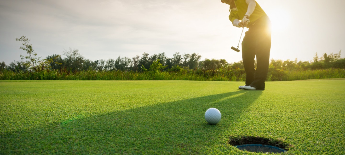 A close-up view of a golf ball and club on the vibrant green fairway, bathed in sunlight during the Riviera Yacht Support Golf Bonanza 2024.