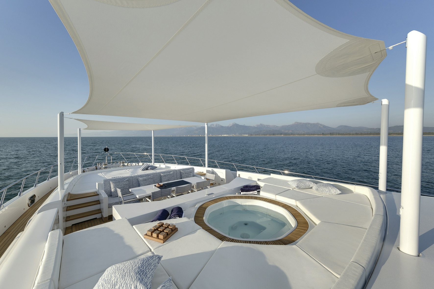 Sundeck Serenity: Jacuzzi with a View on Mangusta 165 Sun-drenched sundeck of the Mangusta 165 yacht with a circular jacuzzi, surrounded by comfortable sun pads and shaded by a stylish canopy.