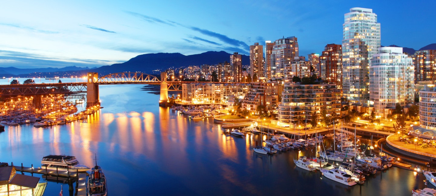 An awe-inspiring aerial view of the Vancouver coast and skyline illuminated by countless city lights during the night.