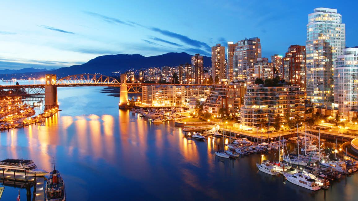 An awe-inspiring aerial view of the Vancouver coast and skyline illuminated by countless city lights during the night.