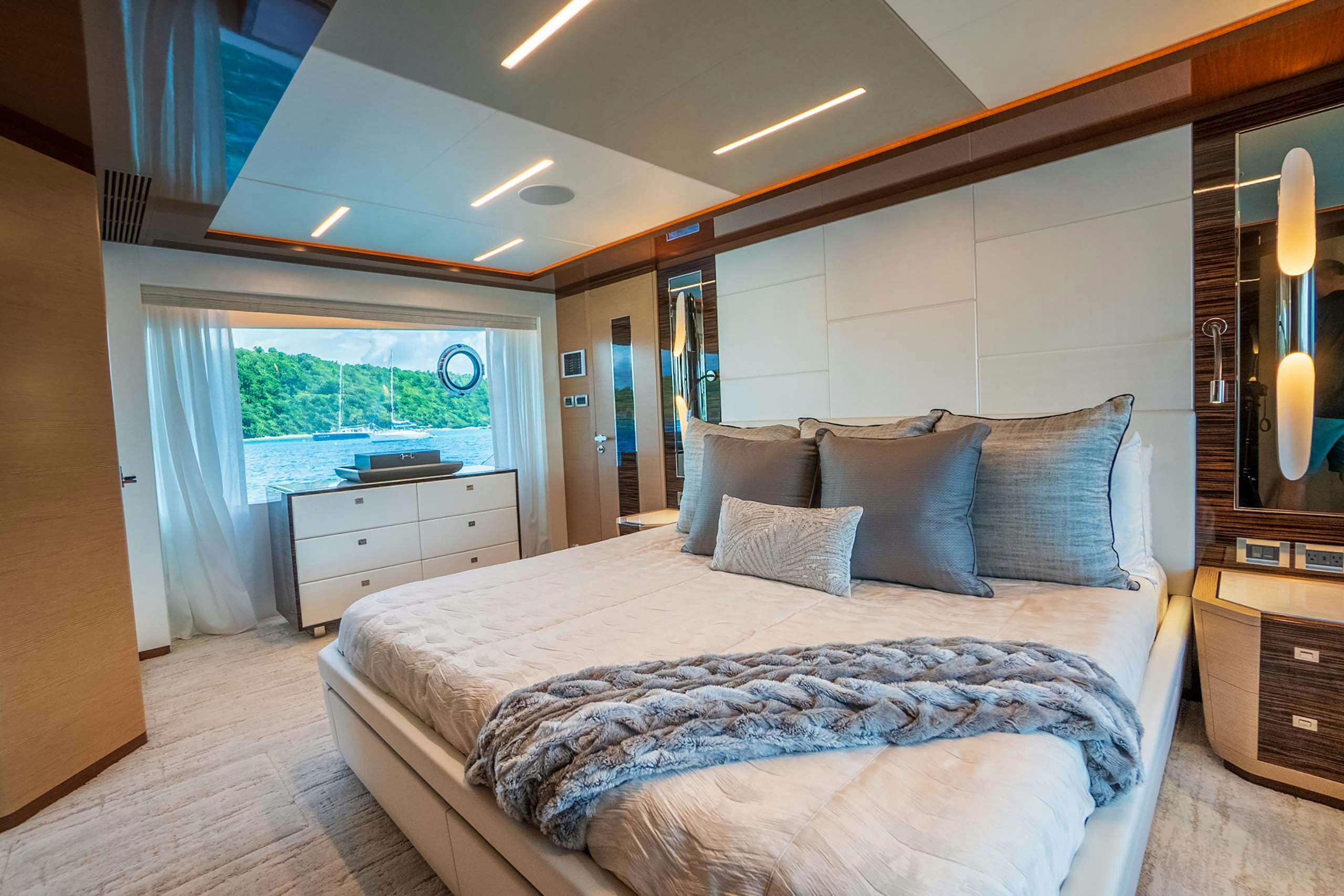 Master stateroom on a 6 to 8 guest charter yacht with king bed and a large window looking out the ocean