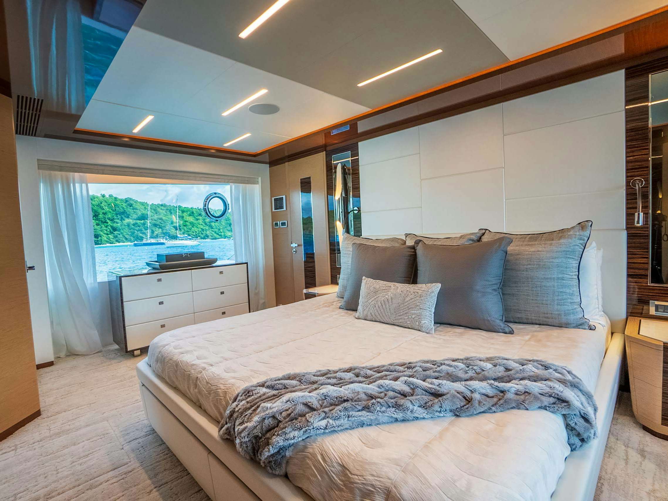 Master stateroom on a 6 to 8 guest charter yacht with king bed and a large window looking out the ocean