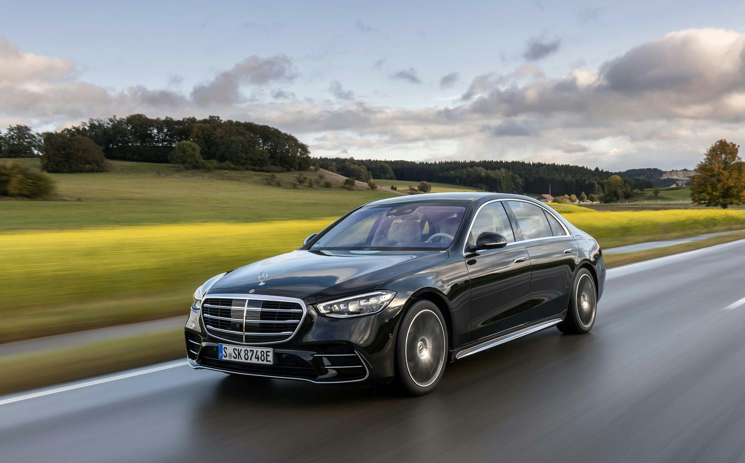 Mercedes-Benz S-Class exterior profile shot of the luxurious black sedan driving across the countryside