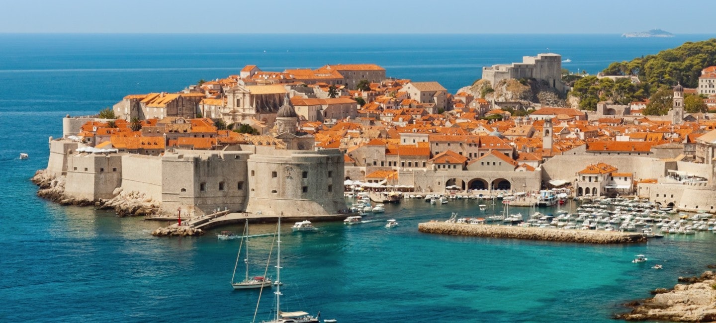 An enchanting aerial view of Dubrovnik's historic old village and picturesque port under the radiant sun during the Dubrovnik Summer Festival.