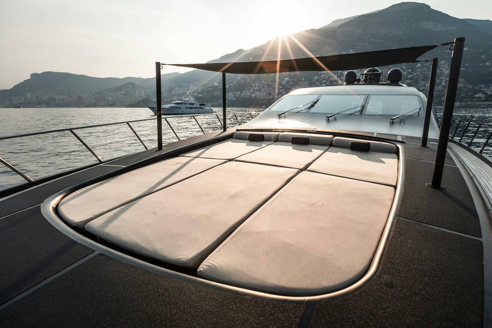The sun deck of the Mangusta 108 yacht during sunset, with the sun casting a warm glow over the lounging area.
