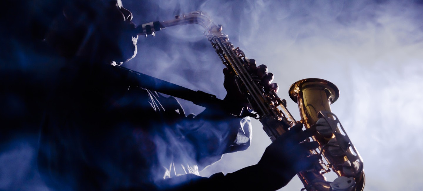 A skilled saxophonist playing passionately in the dimly lit night, enveloped by a mystical fog at the renowned Nice Jazz Festival. To fully enjoy this event, consider chartering an N&J yacht, the ultimate way to experience the festival's magic and music.
