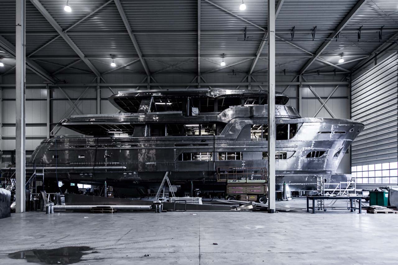 interior of the Van der Valk shipyard, a black superyacht dry docked as it is being worked on