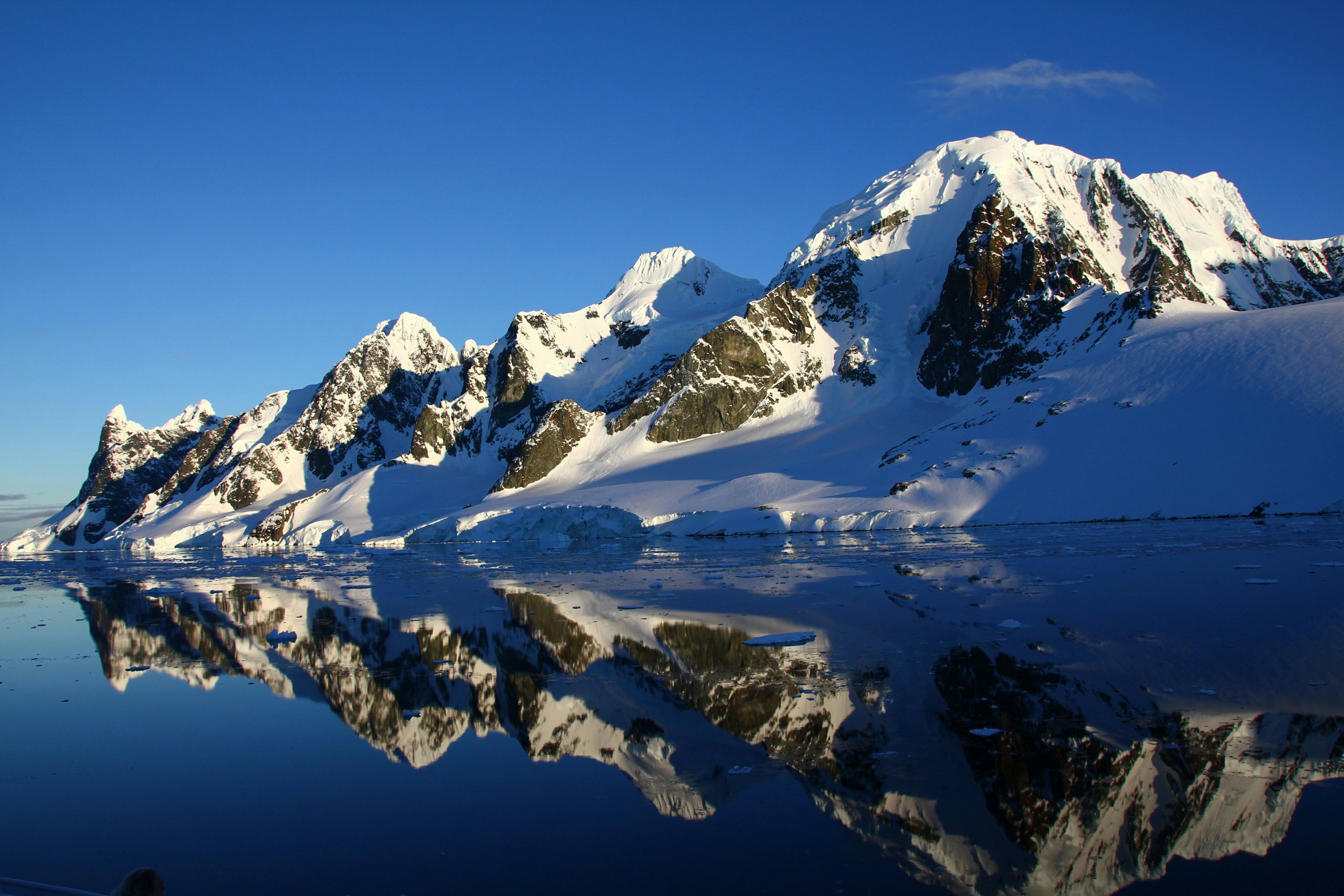 Pristine Antarctic mountain range reflected in the still waters below.
