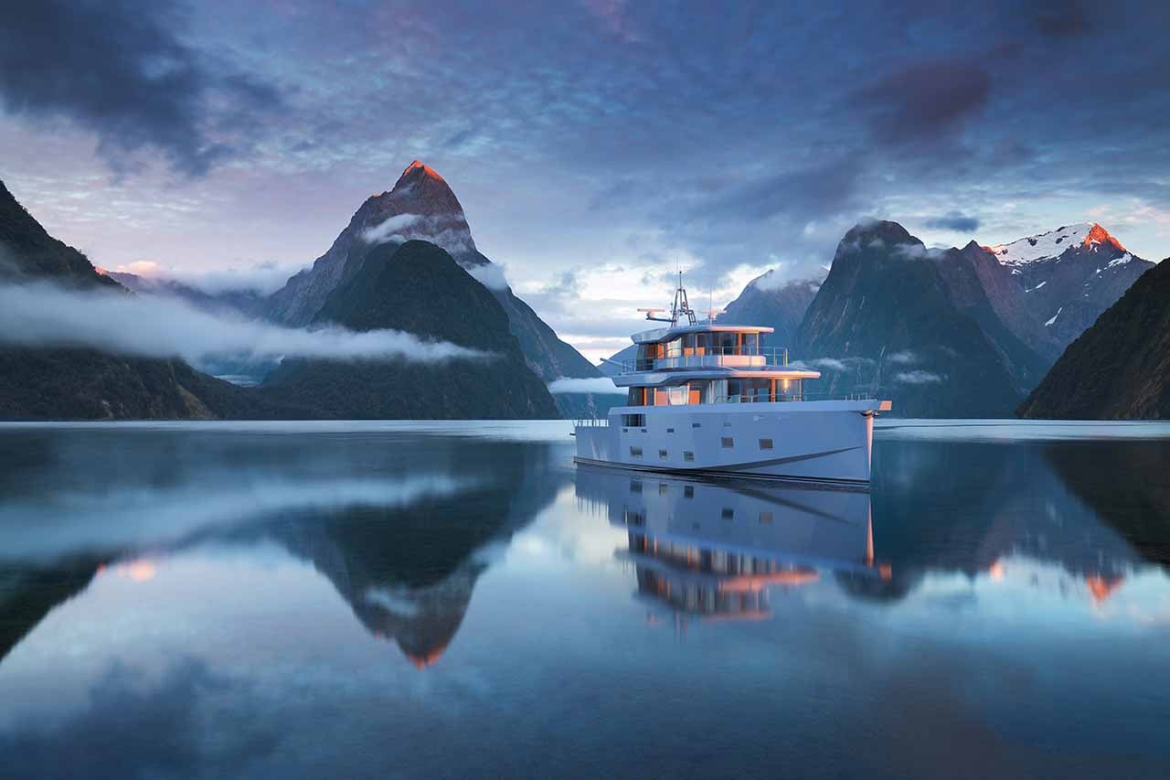 Explorer yacht on a calm blue sea with mountains in the background