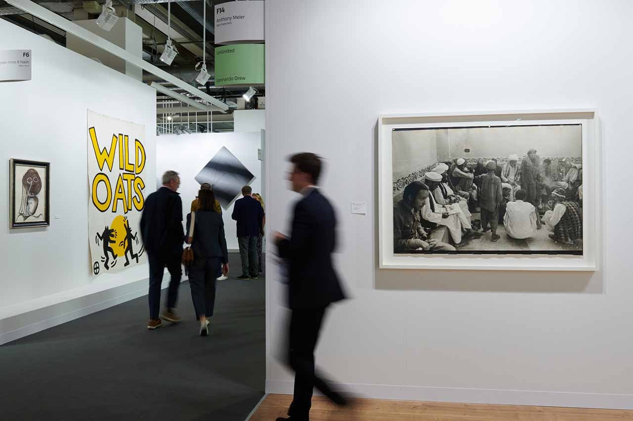 A person walks in front of a black and white photograph on the wall of an art gallery