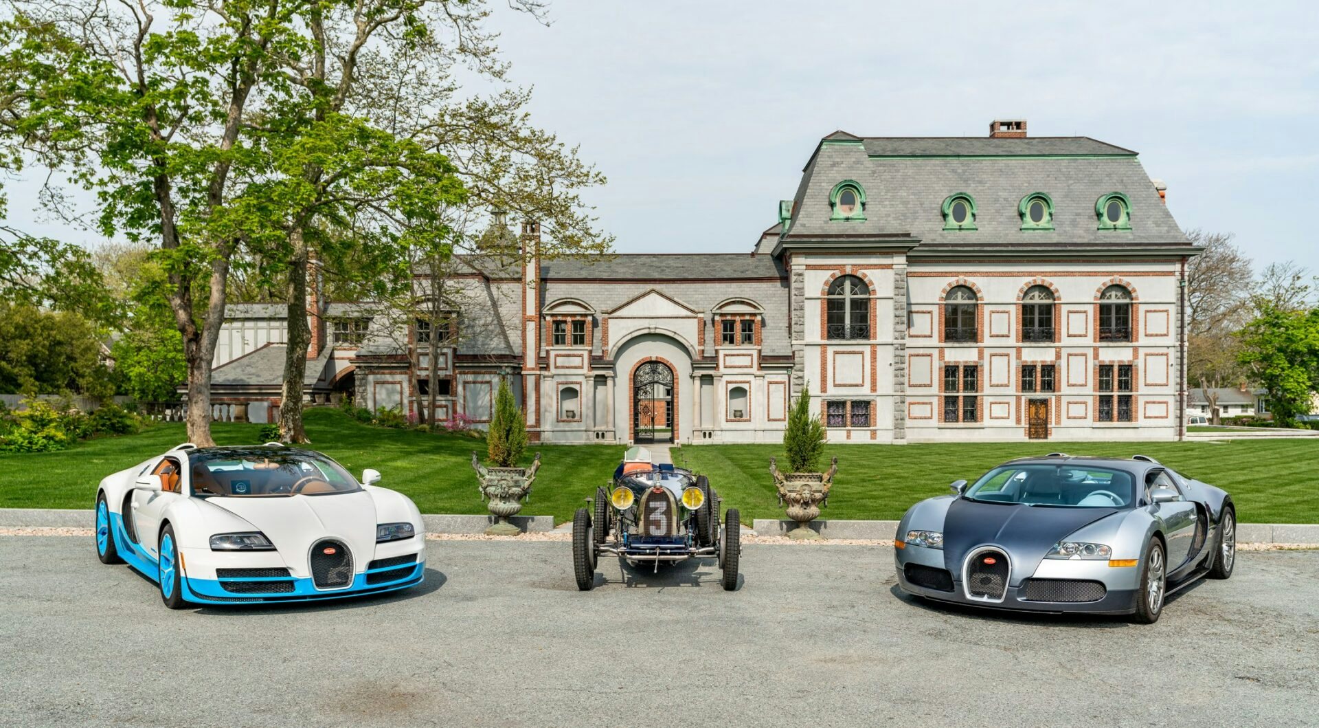 A stunning display of two modern Bugattis and a classic model in front of an elegant mansion in Newport during the Audrain Newport Concours & Motor Week