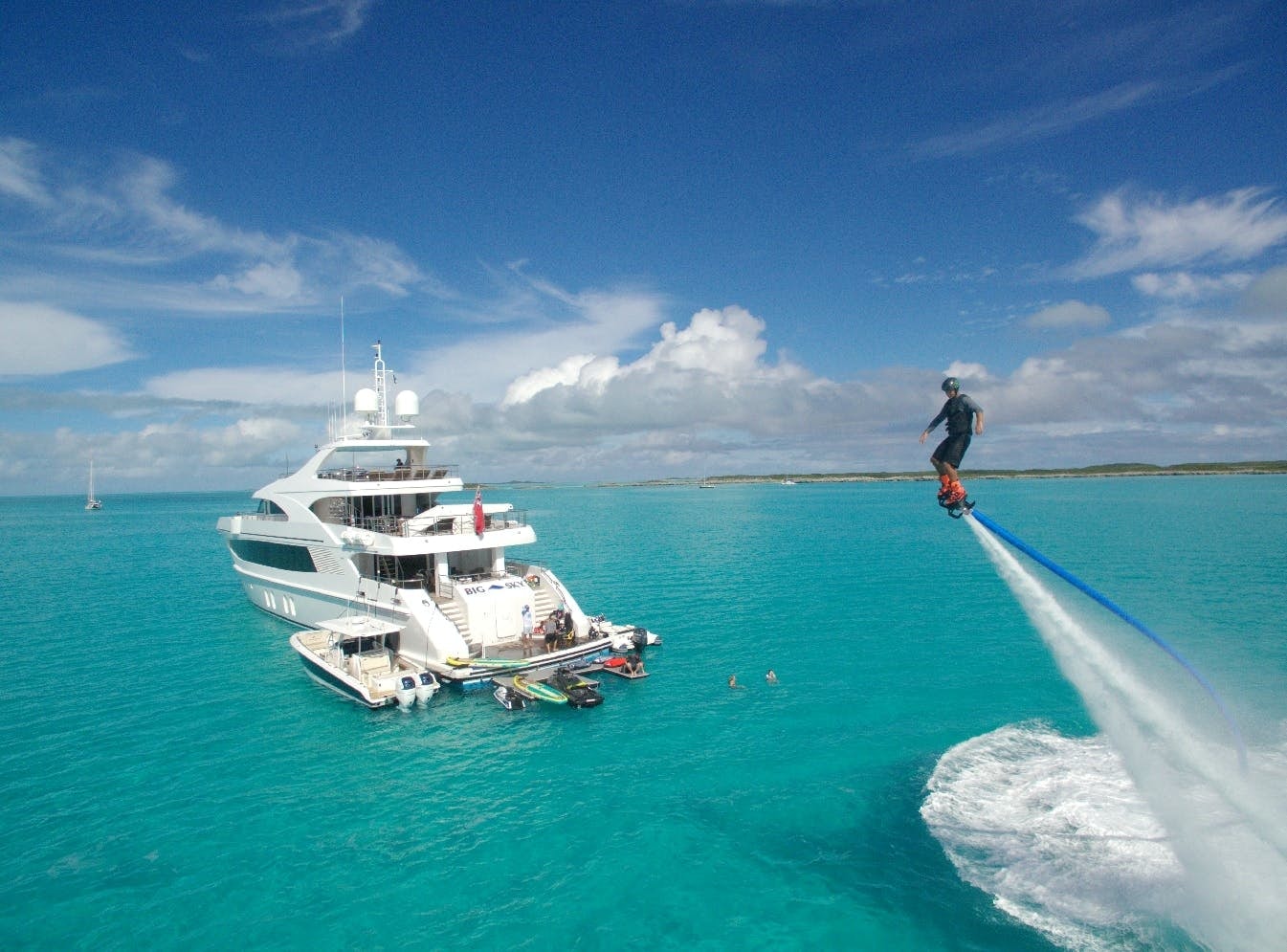 Guest jet packing next to charter yacht BIG SKY on water.