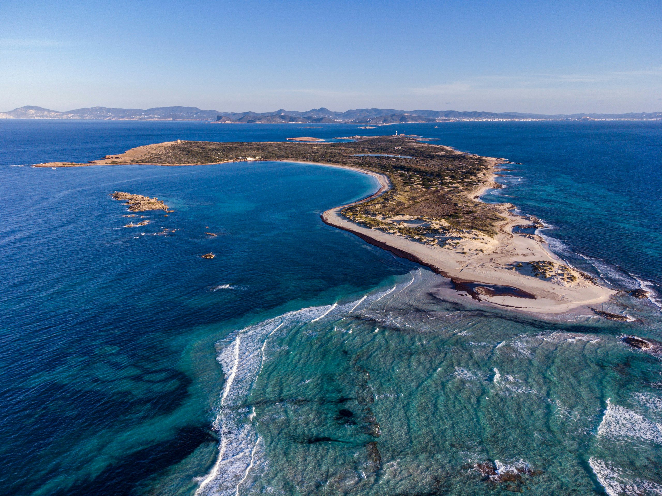 "Peninsula Paradise: Aerial View for N&J Yacht Charter Explorers" Aerial view of a peninsula with clear waters, perfect for exploring with N&J yacht charters in Spain.