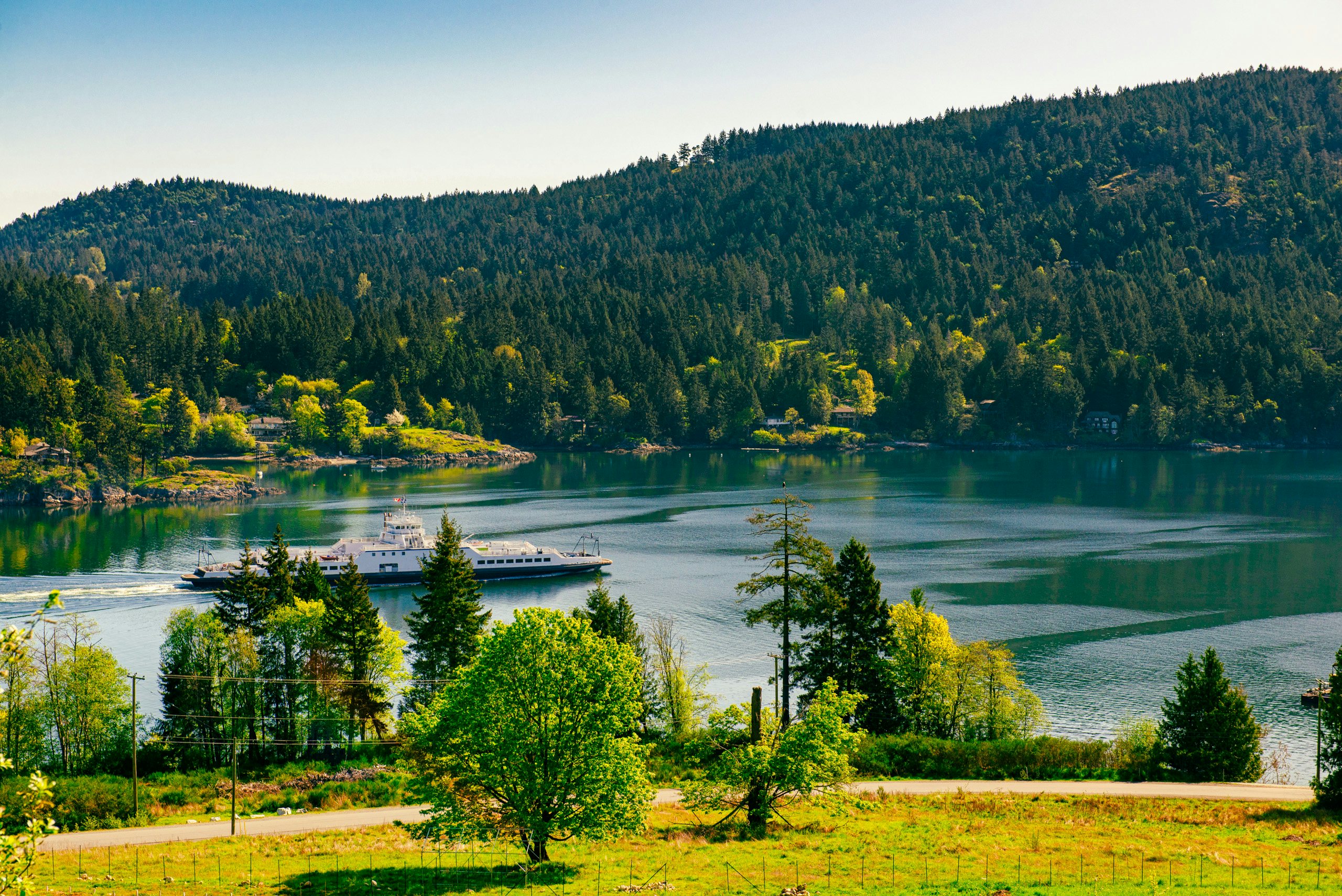 Pacific Northwest Crewed Yacht Charter - View,Of,The,Shoreline,Of,Salt,Spring,Island,With,Ferry Pacific Northwest Crewed Yacht Charter - View of the shoreline of Salt Spring Island with ferry crusing the water, British Columbia, Canada