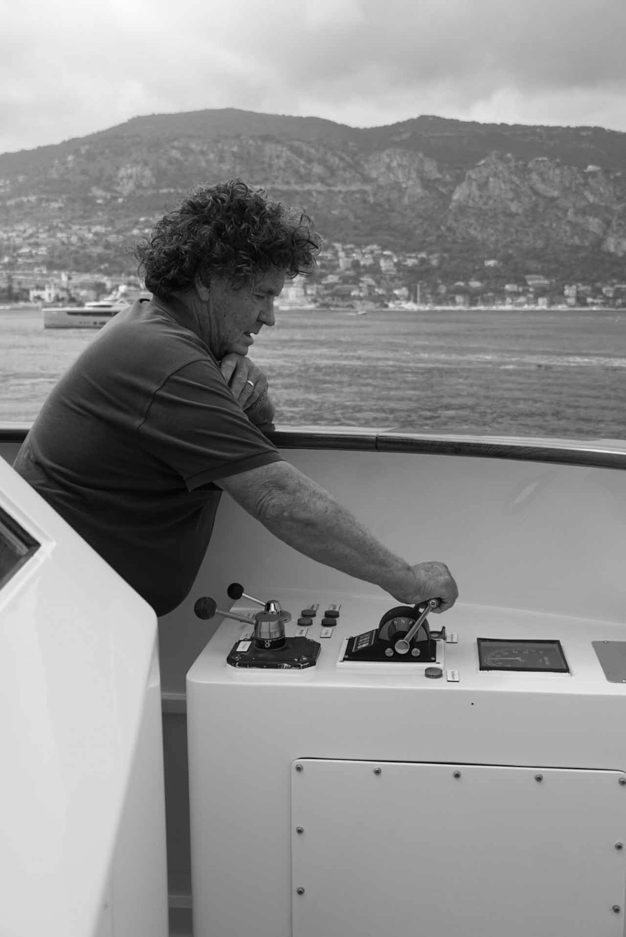 Black and white photo of Captain Neil Batt in profile, the bay of Beaulieu-sur-Mer int he background