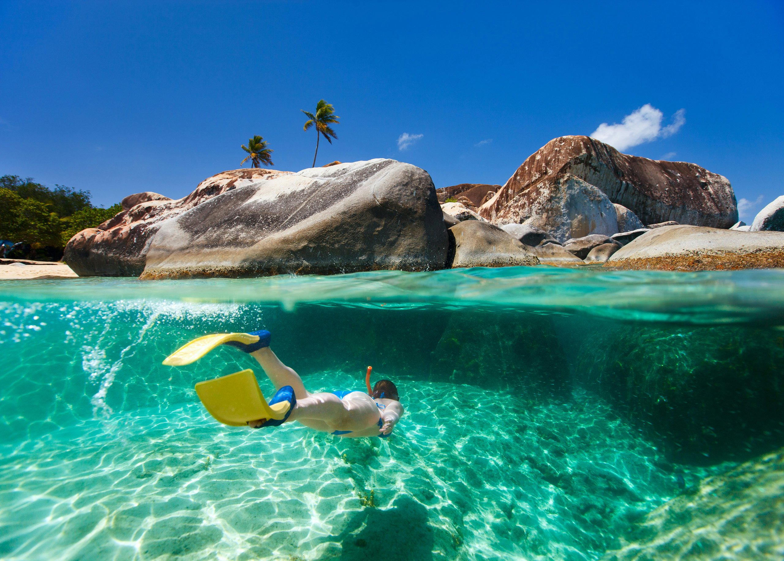 BVI Superyacht Splendor: Picturesque Waters with Snorkeling Adventure A captivating scene of a woman snorkeling beneath the crystal-clear waters of the BVI, Caribbean, with a scenic island in the background—a perfect moment on your BVI Superyacht Charter.