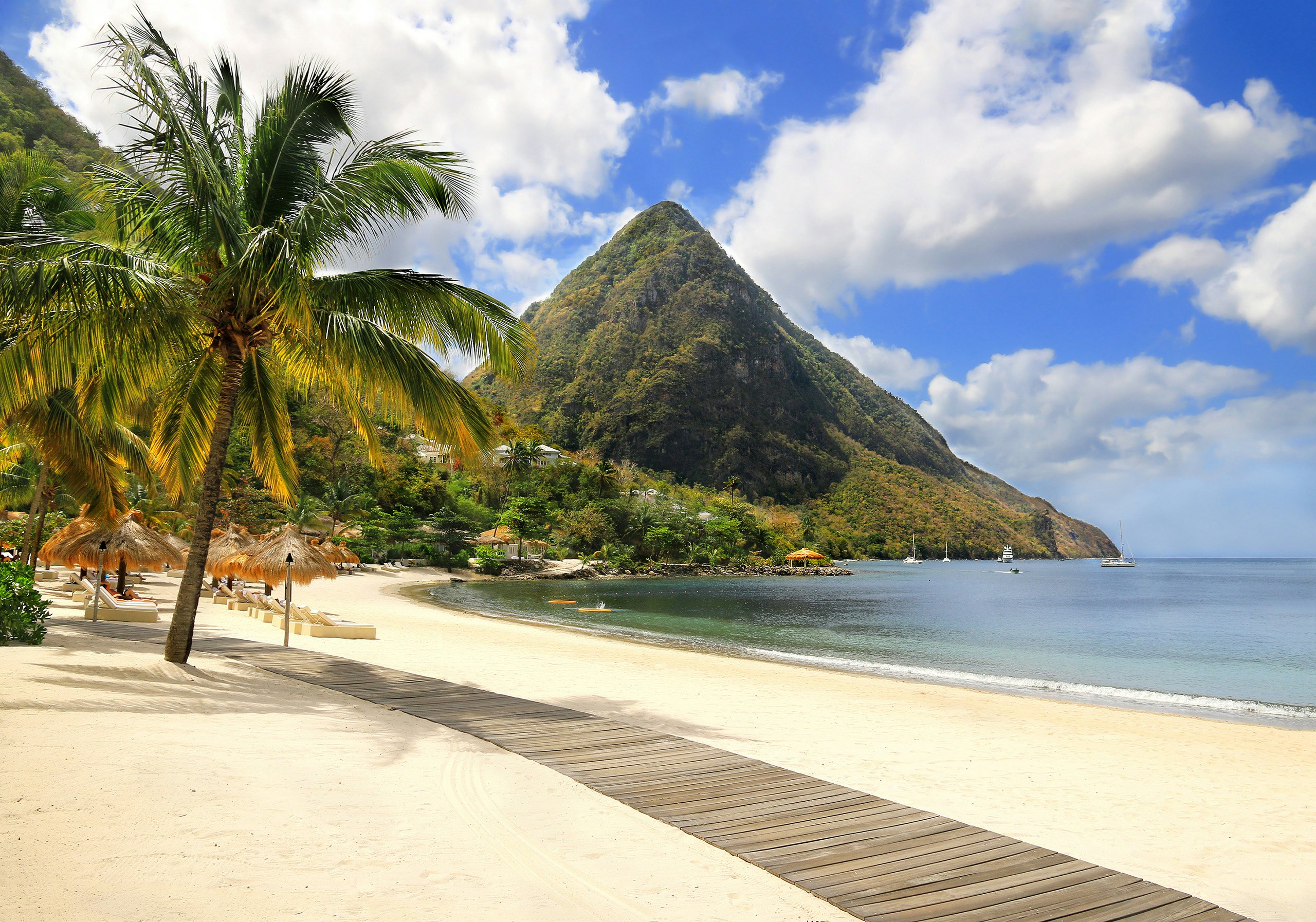 A mesmerizing view of St. Lucia during the day, showcasing white sand beaches, untouched nature, and a backdrop of high, pointed mountains—a perfect scene for your Caribbean Windward St. Lucia Charter Yacht adventure.