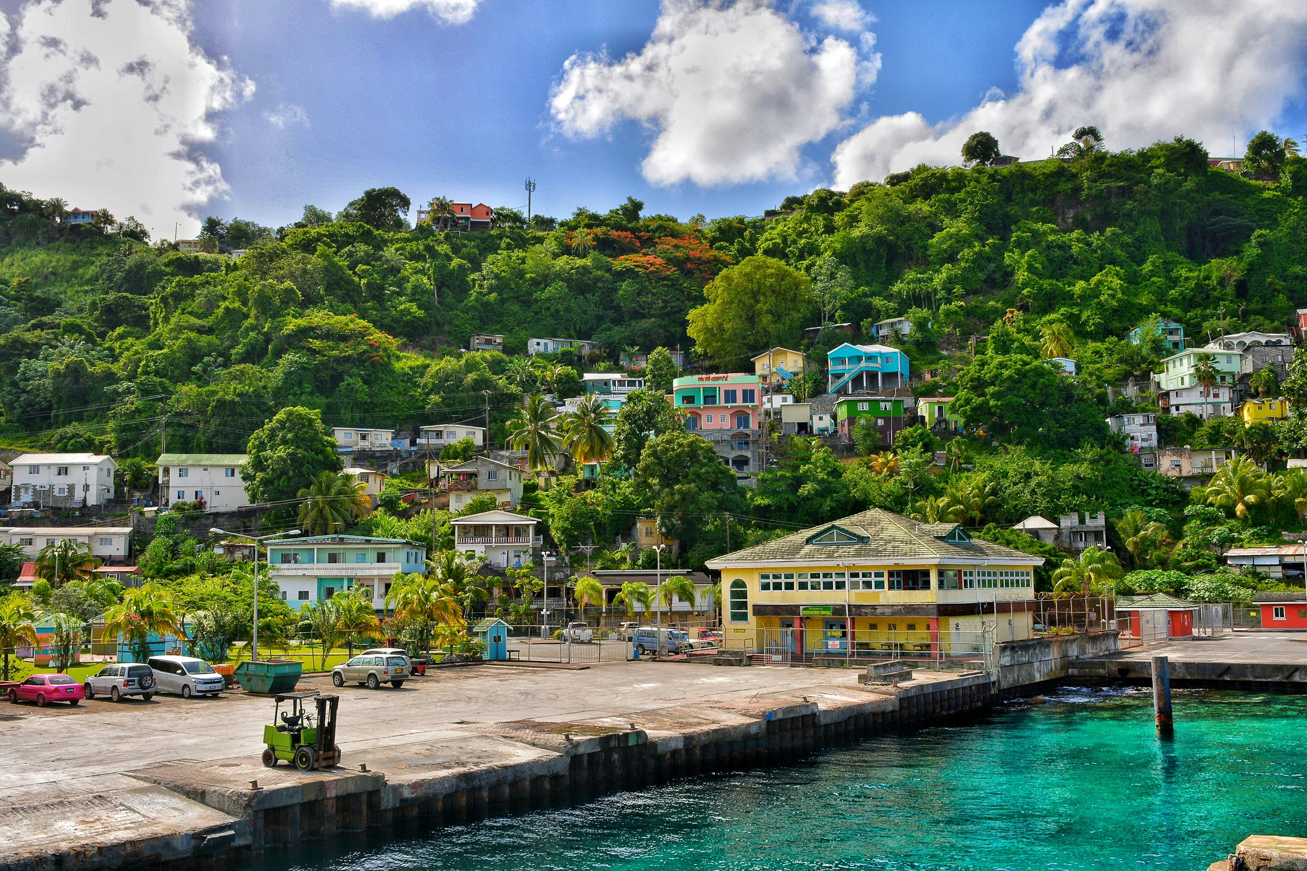 Grenadines Luxury Yacht Charms: Kingstown's Hillside Villas Amidst the Caribbean Blue Mirror A mesmerizing view of Kingstown in St. Vincent and the Grenadines, showcasing stunning colored villas standing on the hill in front of a serene blue mirror of the Caribbean Sea—a picturesque scene for a Grenadines Luxury Yacht Charter.