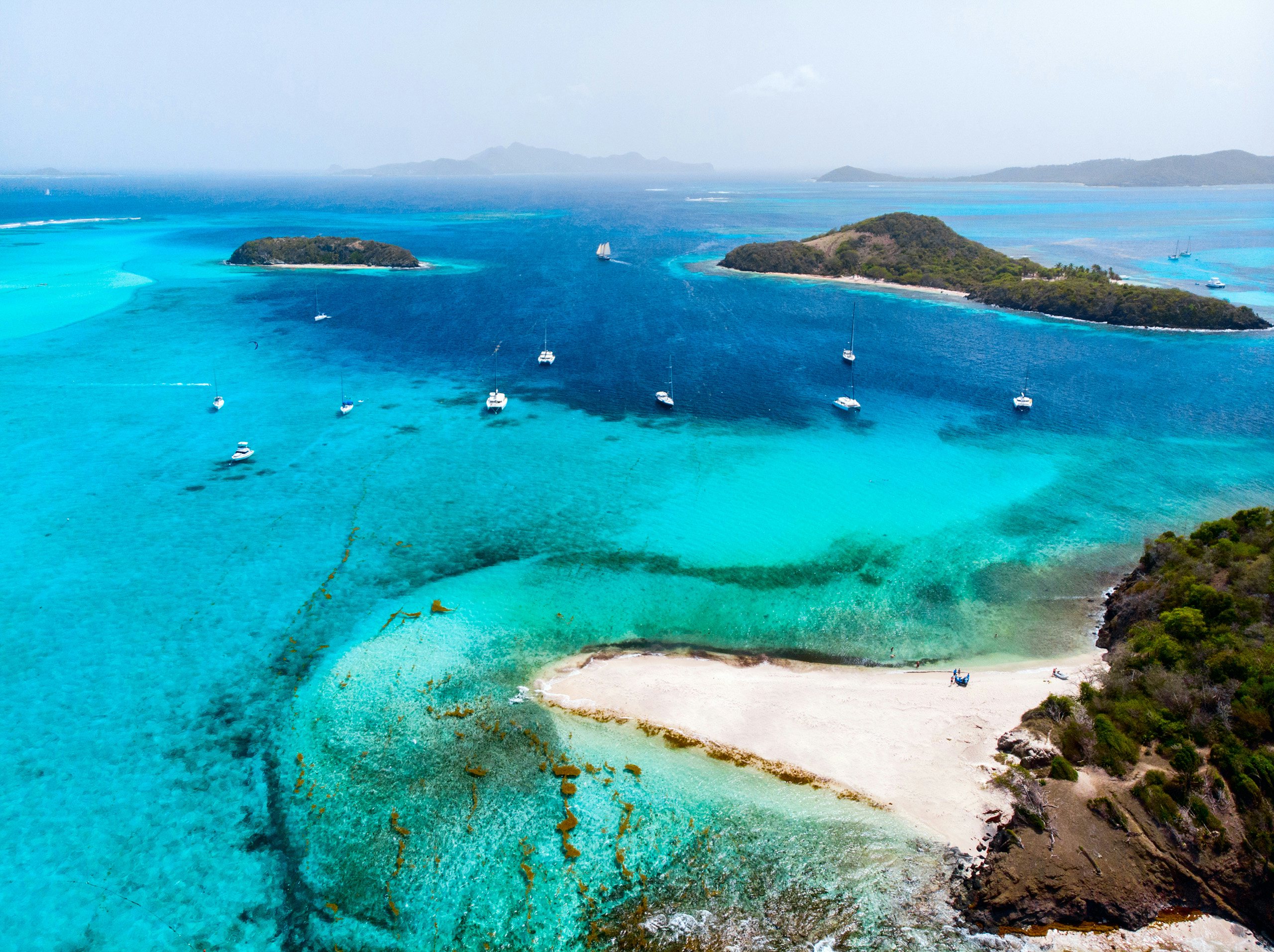Tobago Cays Aerial Splendor: Trinidad & Tobago Superyacht Charter An awe-inspiring aerial drone view of the tropical islands and turquoise Caribbean Sea of Tobago Cays in St. Vincent and the Grenadines—a paradise awaits for Trinidad & Tobago Superyacht Charter.