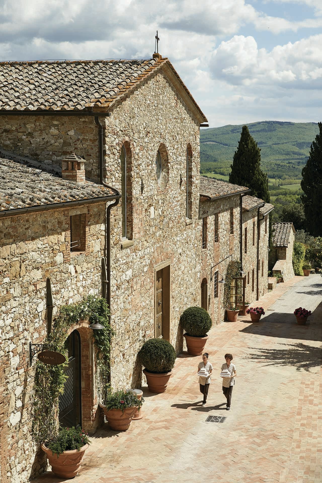 Stone buildings and two women running by them