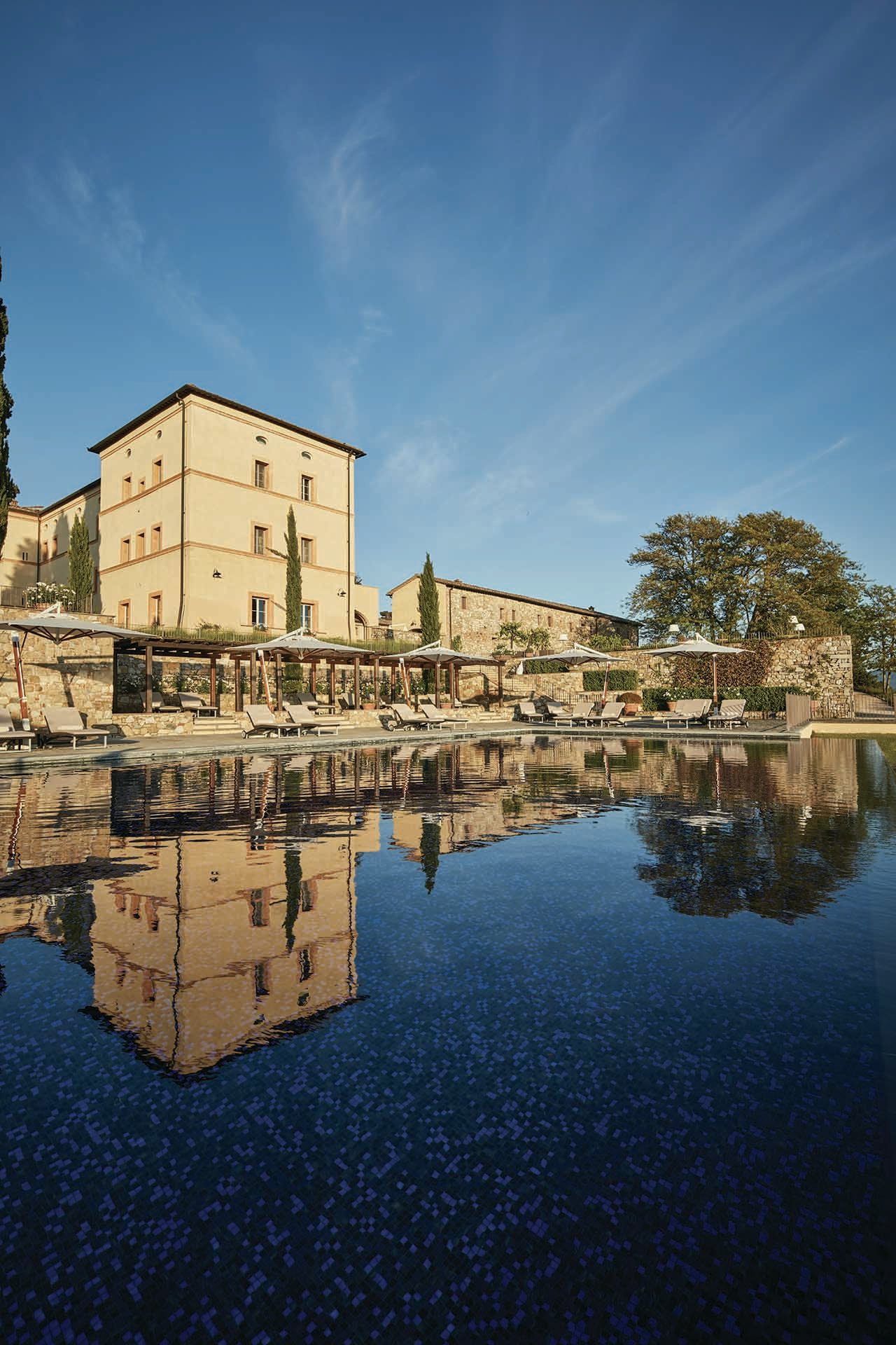 View of Castello di Casole buildings with the reflection in a small lake