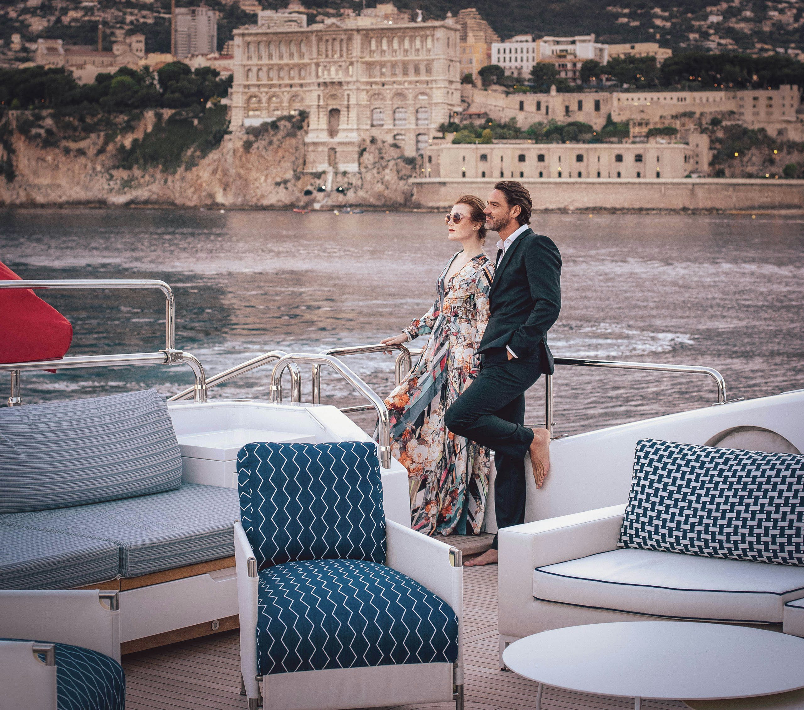 Glamorous Mediterranean Yacht Charter Experience During Cannes Film Festival An elegant couple leans affectionately against the railing of a luxurious yacht, gazing out at the riviera coastline during the Cannes Film Festival.