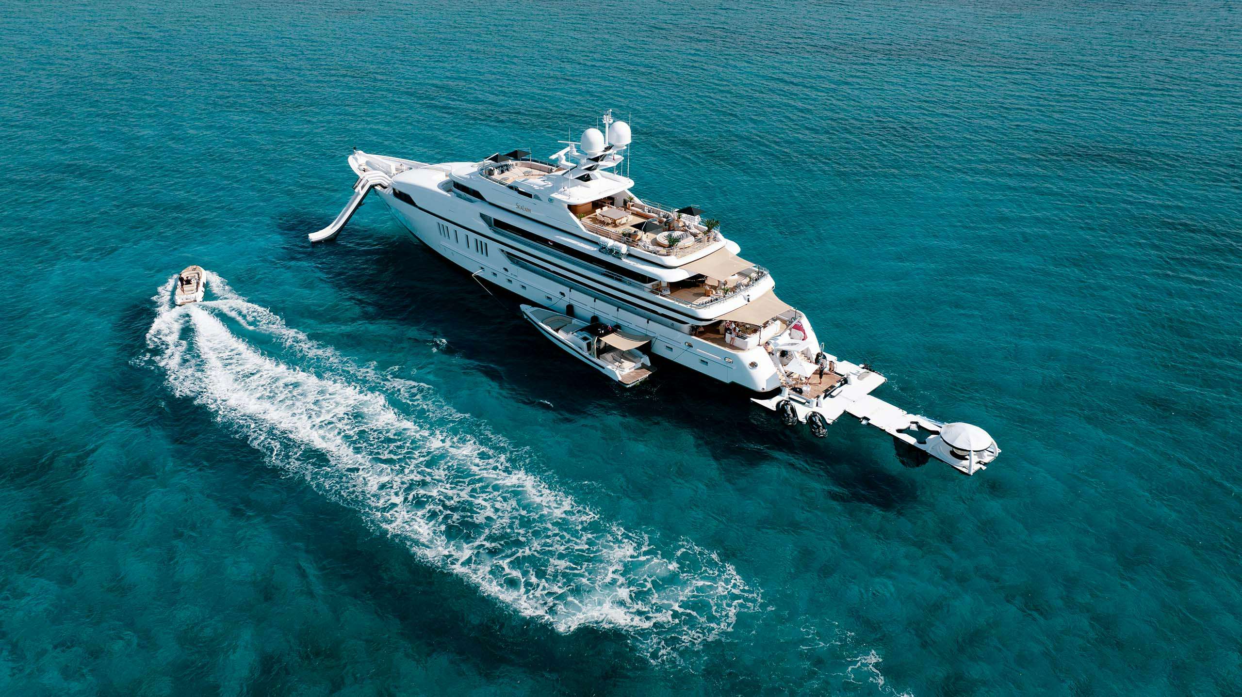 Superyacht anchored in the Bahamas with tender navigating around it