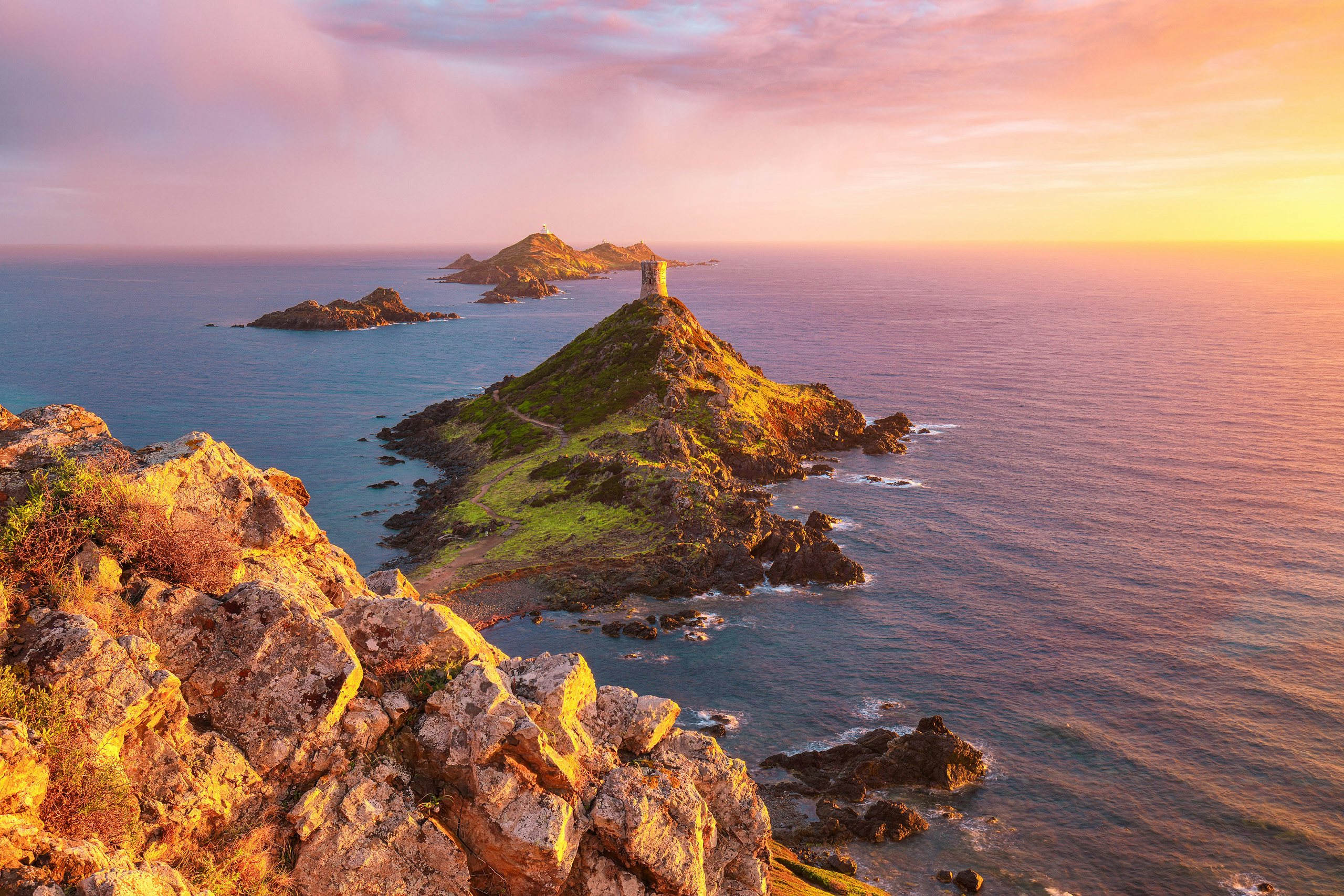 Ajaccio's Rocky Shores | Yacht Charter Escapes | Northrop & Johnson Clear blue waters wash over the rocky beaches of Ajaccio, Corsica, with vibrant city architecture in the distance.