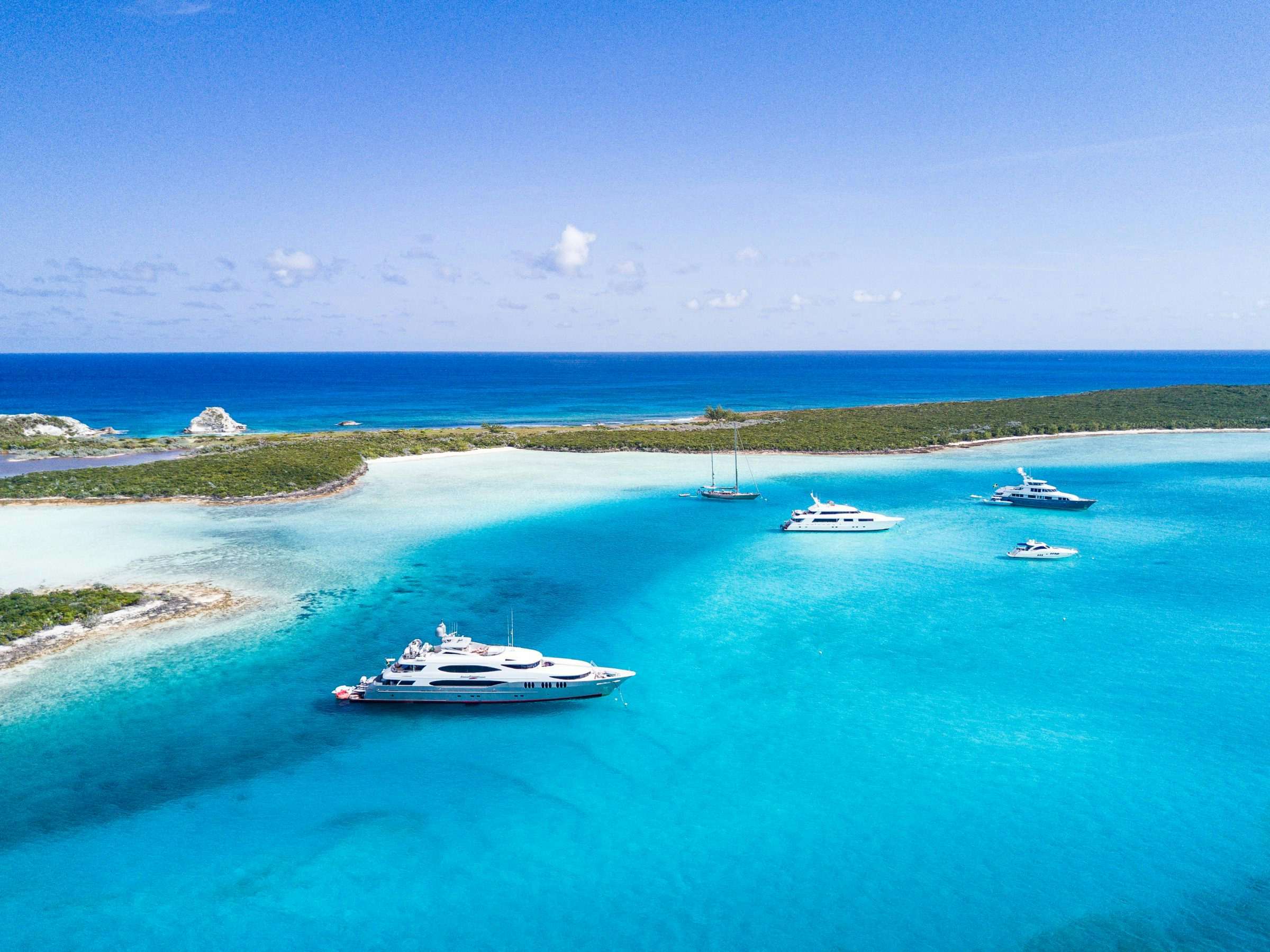 group of tandem superyacht charters at anchor in blue caribbean waters of bahamas