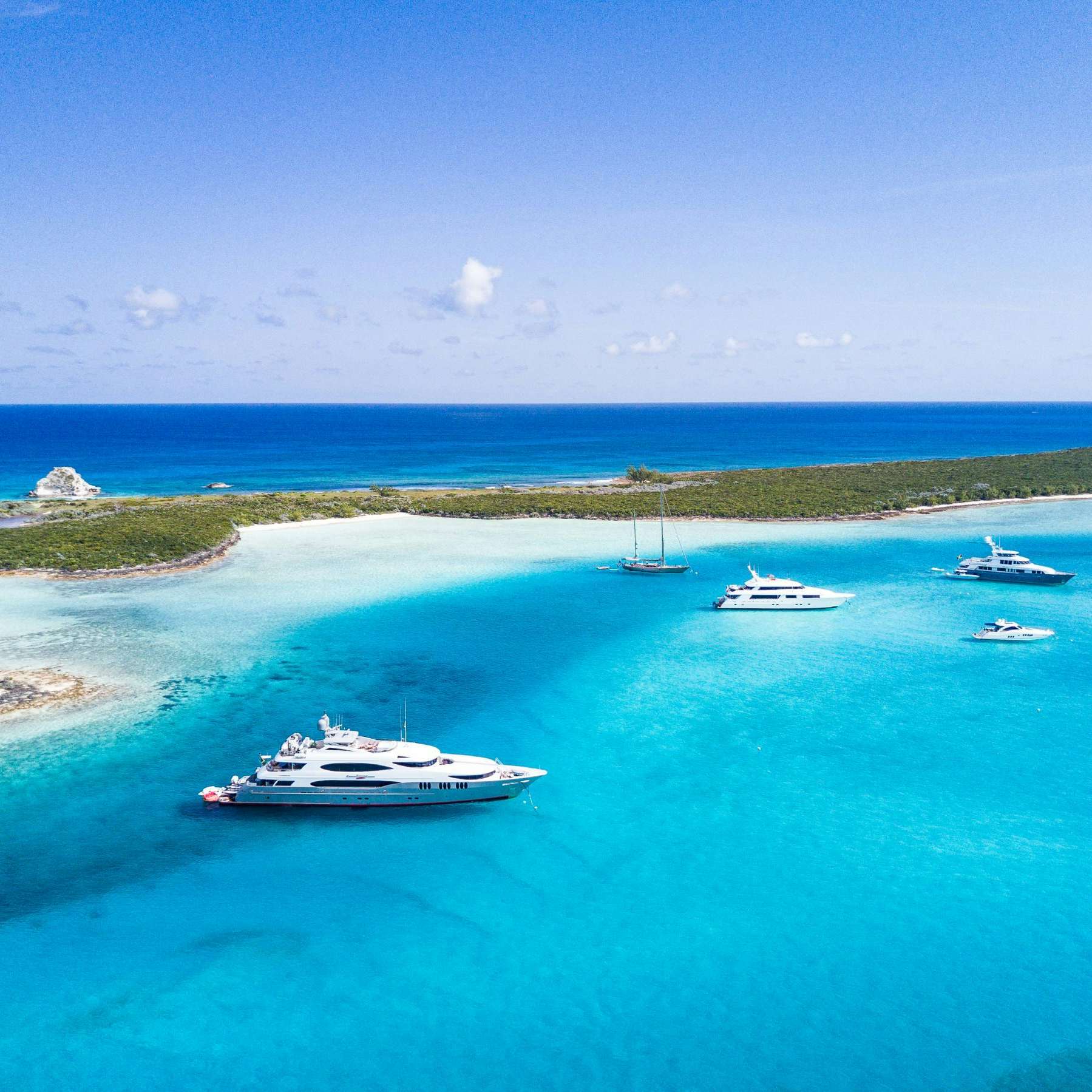 group of tandem superyacht charters at anchor in blue caribbean waters of bahamas