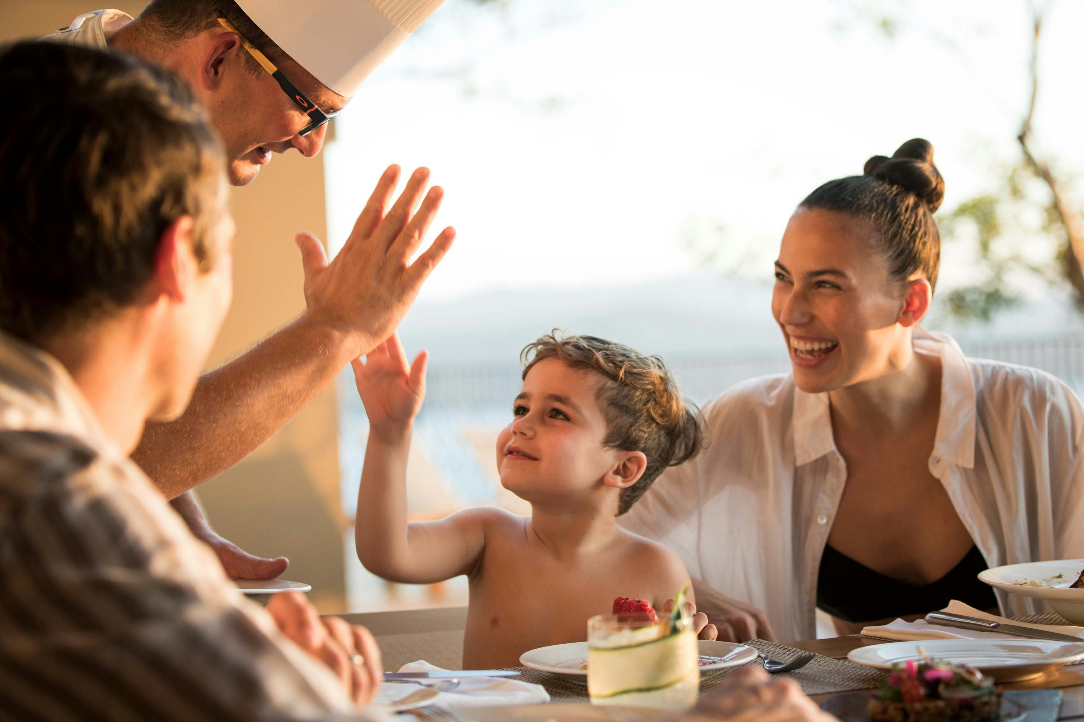 Exclusive Resorts members and child laughing with a chef in a luxury destination