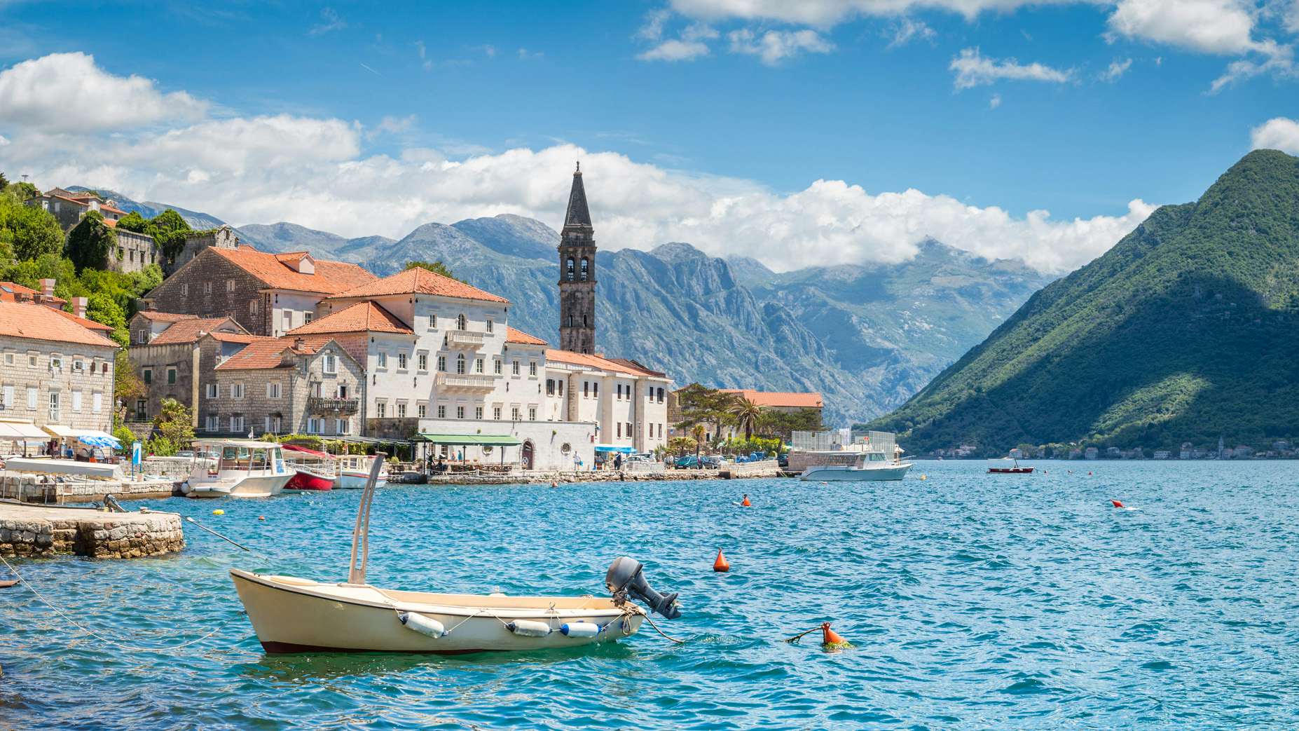 The picturesque coastal town in Montenegro, with historic architecture and a backdrop of majestic mountains, seen from the sea.