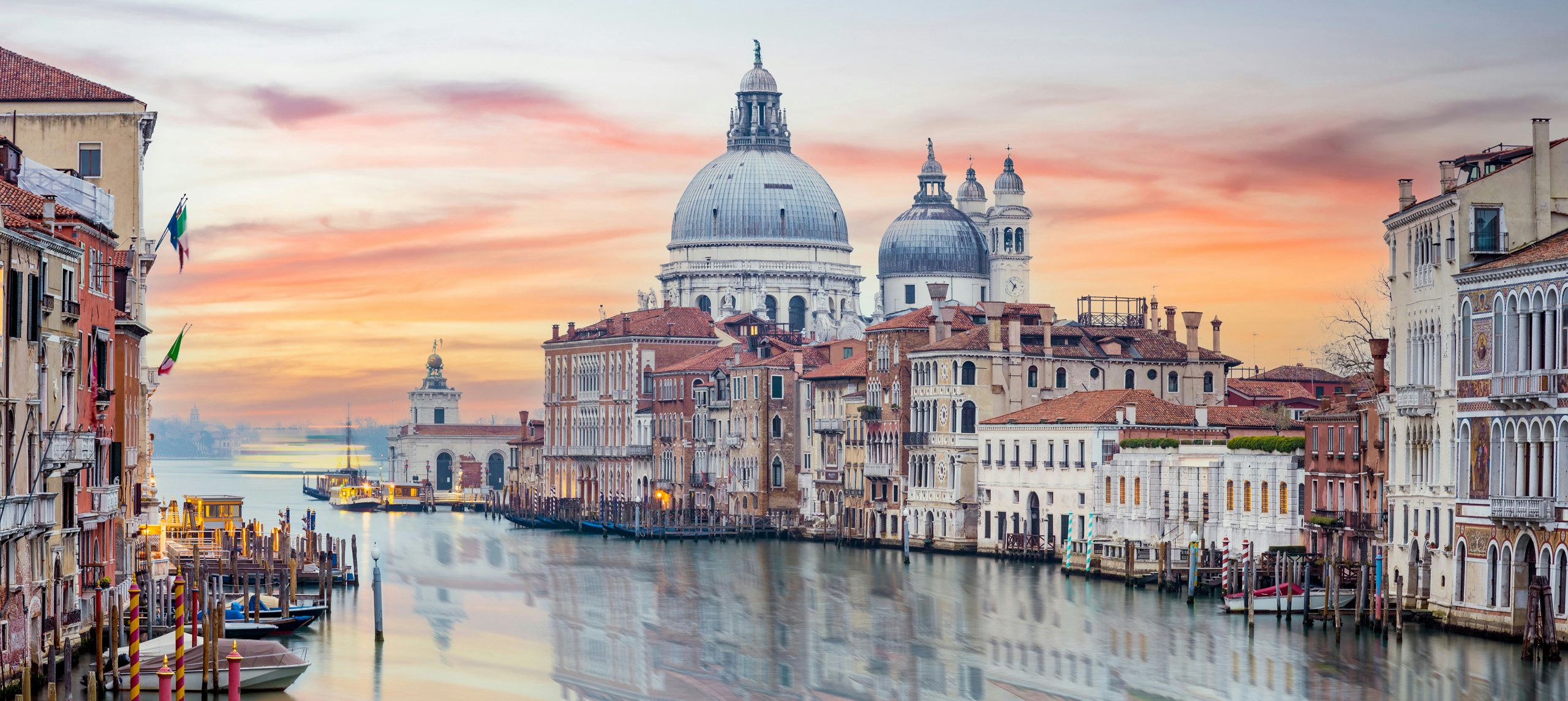 The iconic Santa Maria della Salute Basilica against a pastel sunset sky in Venice.