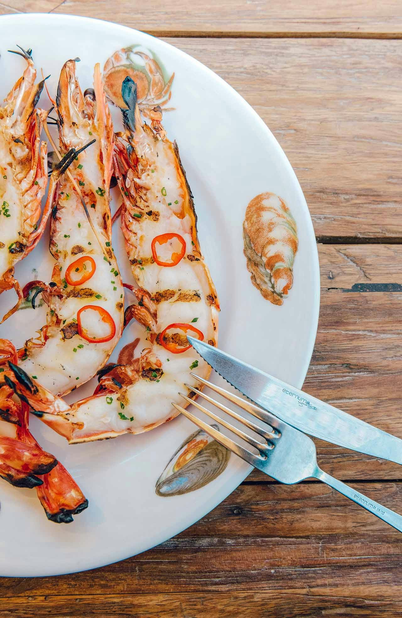 Grilled shrimp scampi cut in half on a white plate