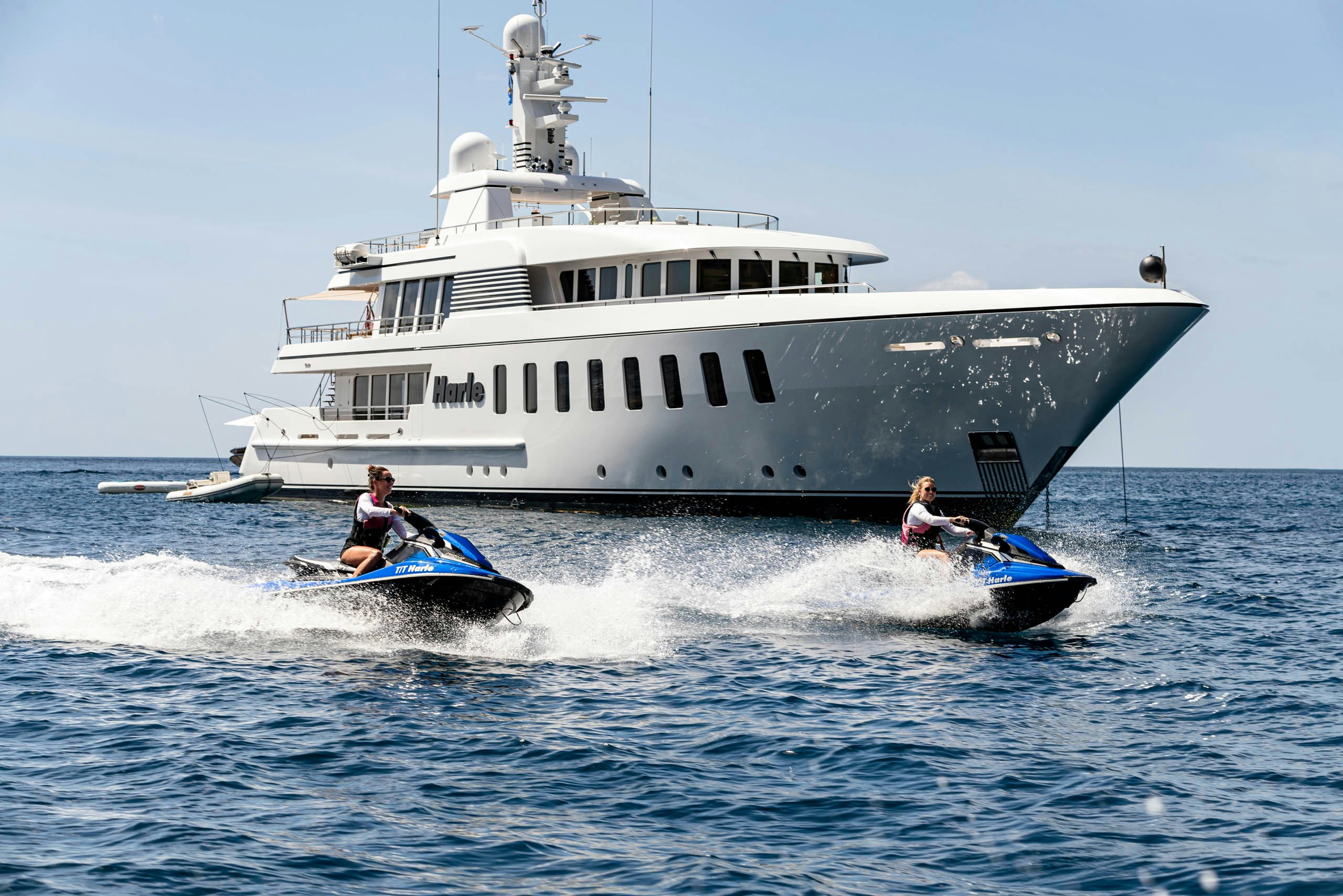 Jet skis cruise in front of white motor yacht harle in the ocean
