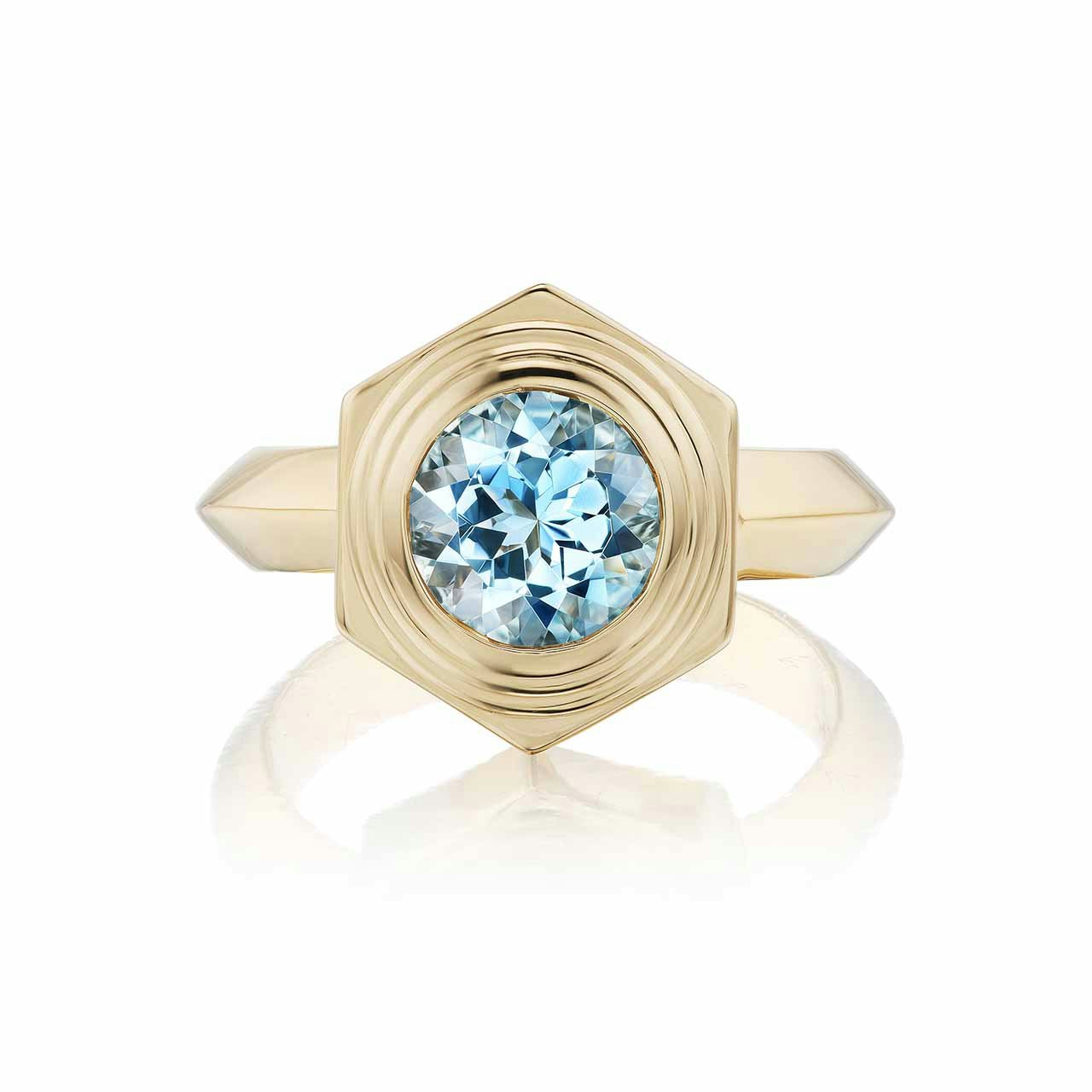A gold ring with hexagonal setting with a light blue stone in the middle