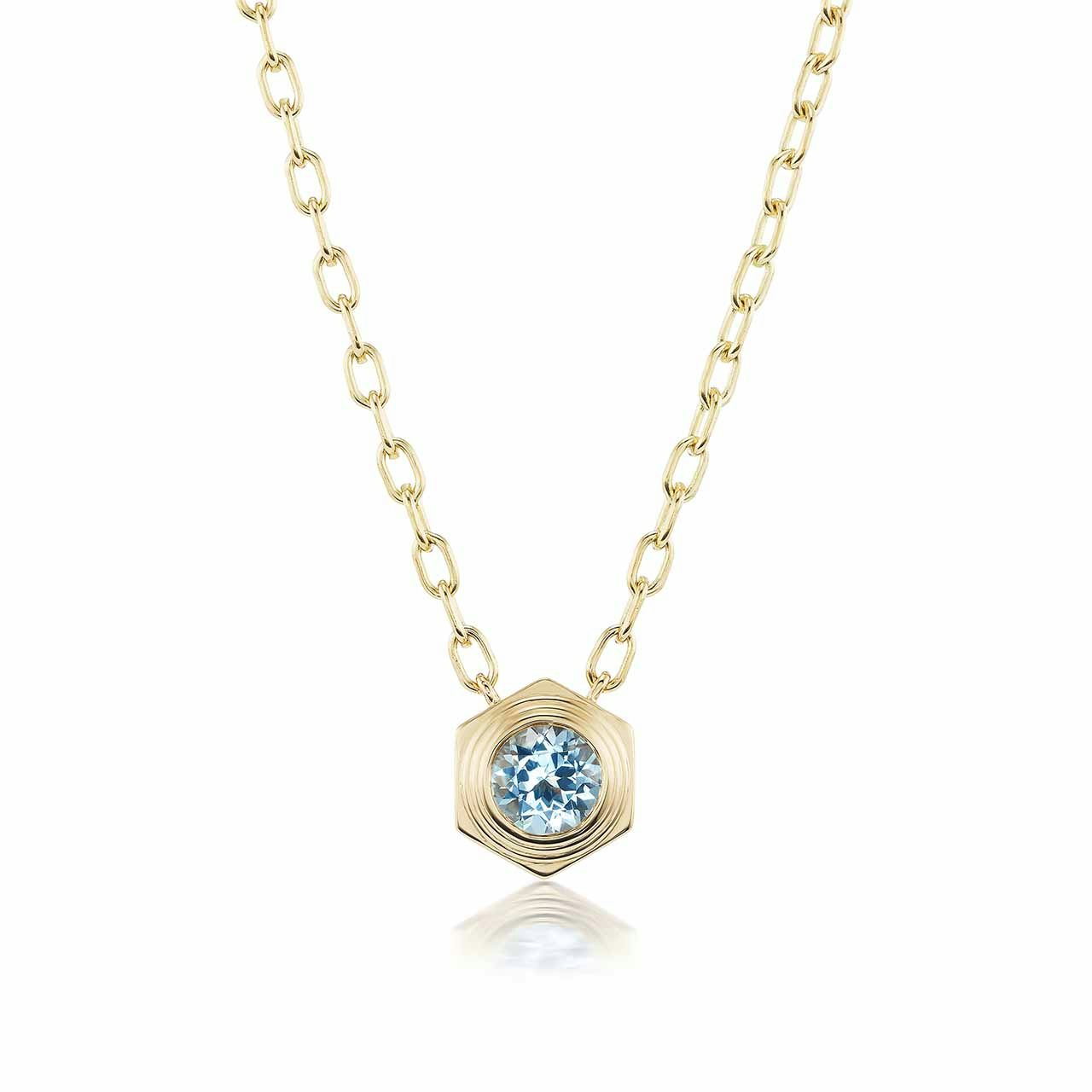 A gold necklace with hexagonal pendant with a light blue stone