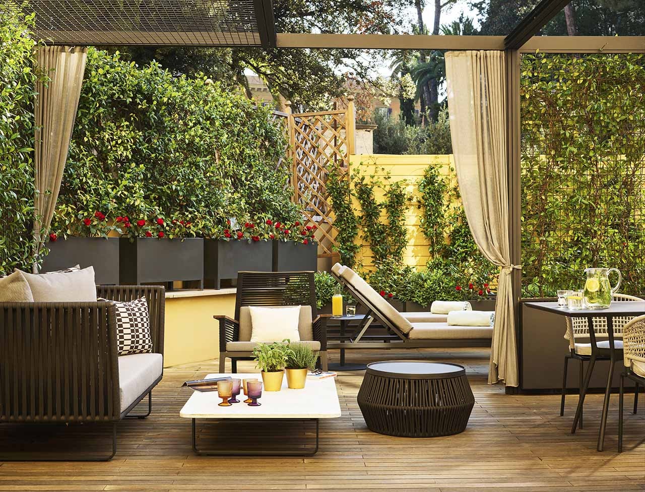 A courtyard garden with low seating around a dining table and lounge chairs in the background