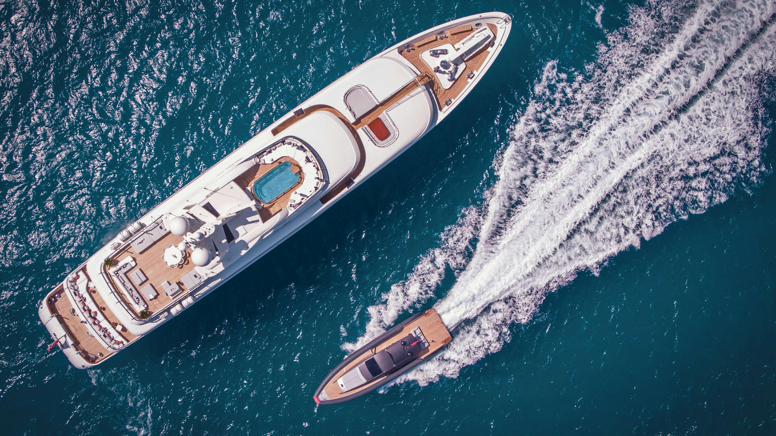 Tender passing by superyacht at anchor