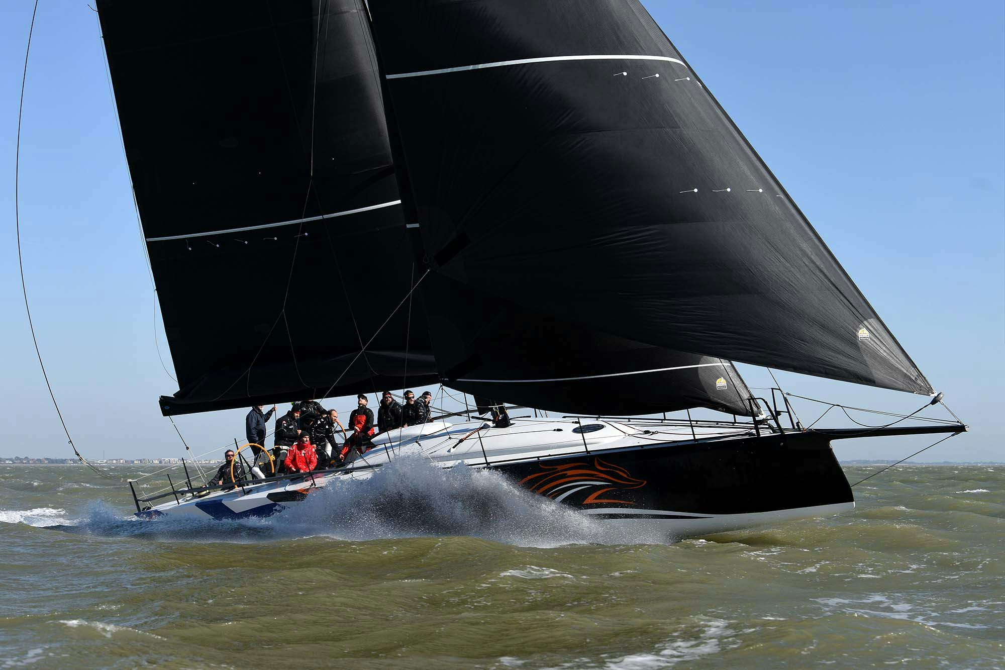 infiniti 52 sailing yacht with dramatic black sails in the ocean