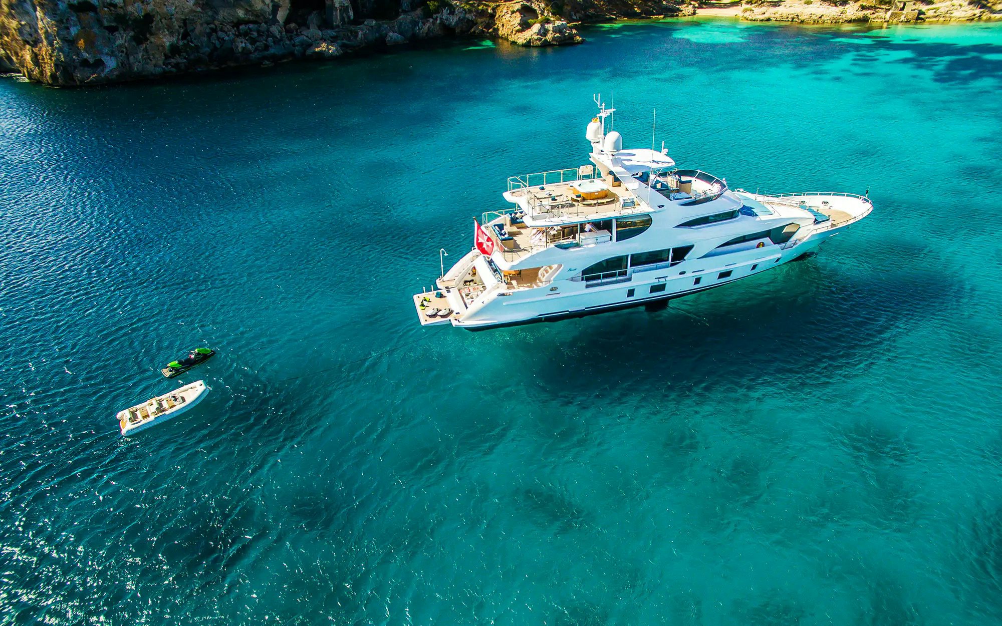 image of superyacht JUS CHILL&#039;N 3 at anchor in crystal blue waters with a tender behind it