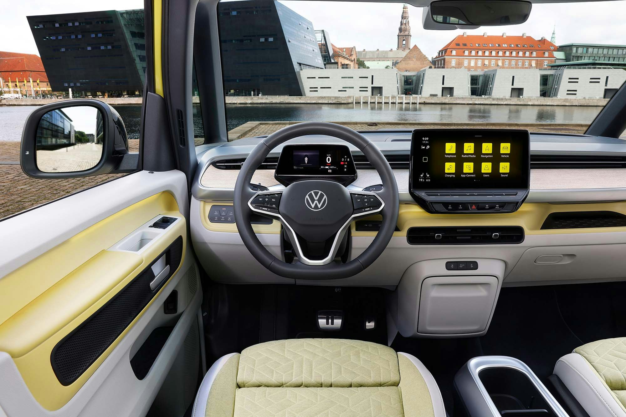 VW ID Buzz close up of the steering wheel with yellow and white leather seats and a modern dashboard with view of a city through the windshield