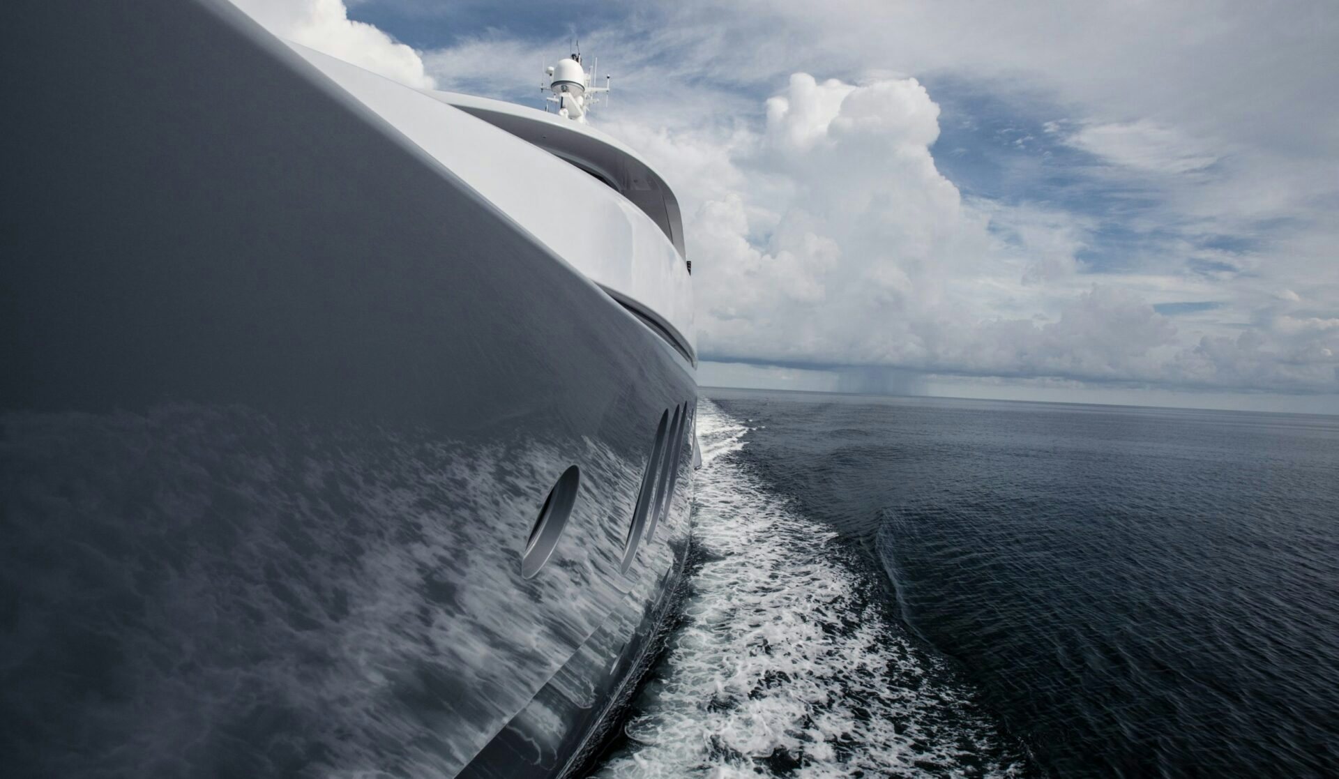 Side close-up of an Abeking & Rasmussen yacht cruising through the ocean, showcasing the vessel's smooth lines and powerful movement.