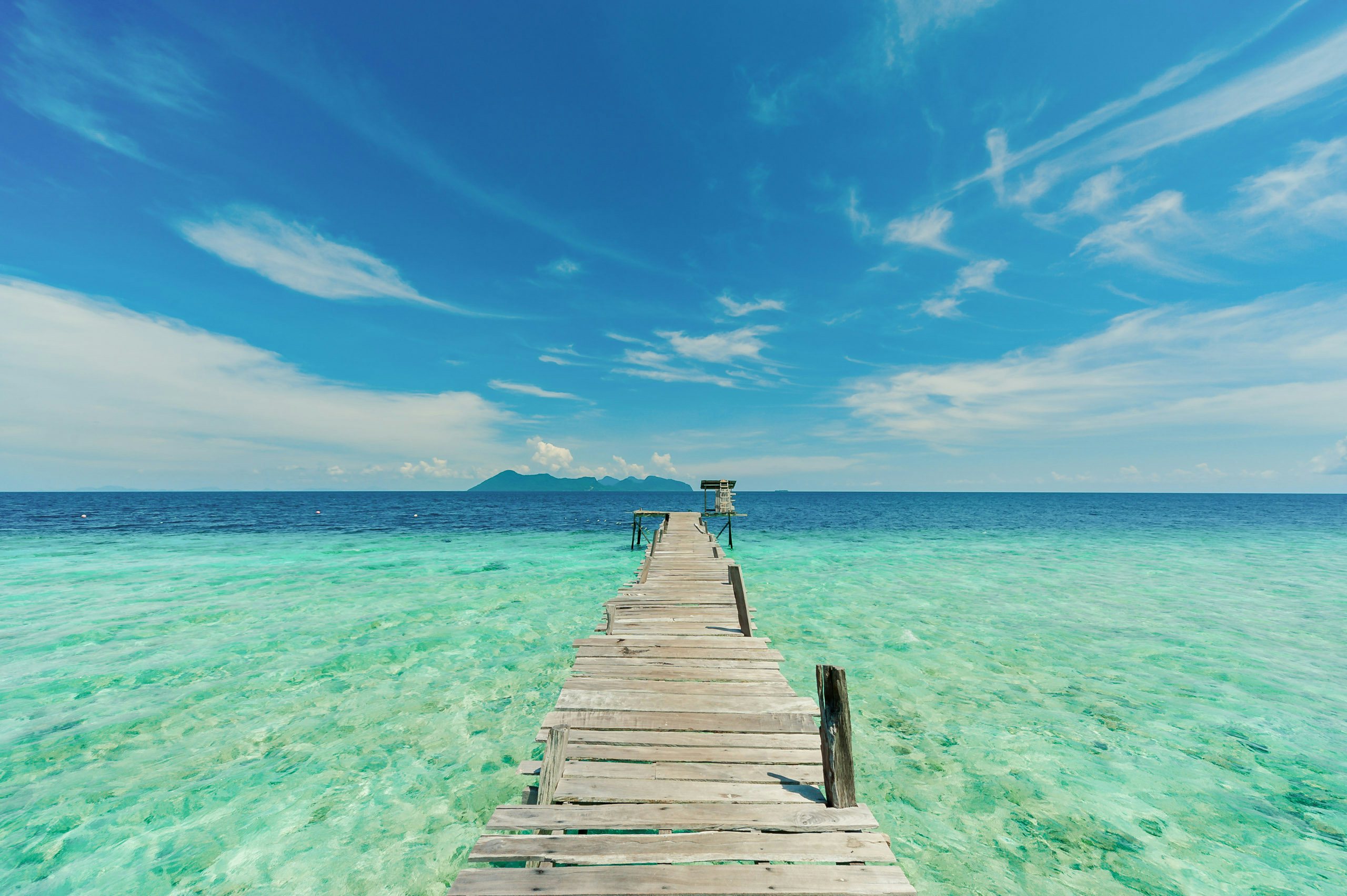 Malaysia Superyacht Charter - Wooden pier or jetty heading toward the horizon Malaysia Superyacht Charter - A wooden pier or jetty heading toward the horizon on a crystal clear sea water beach at Pom Pom Island Sabah, overlooking the Boheydulang Island.