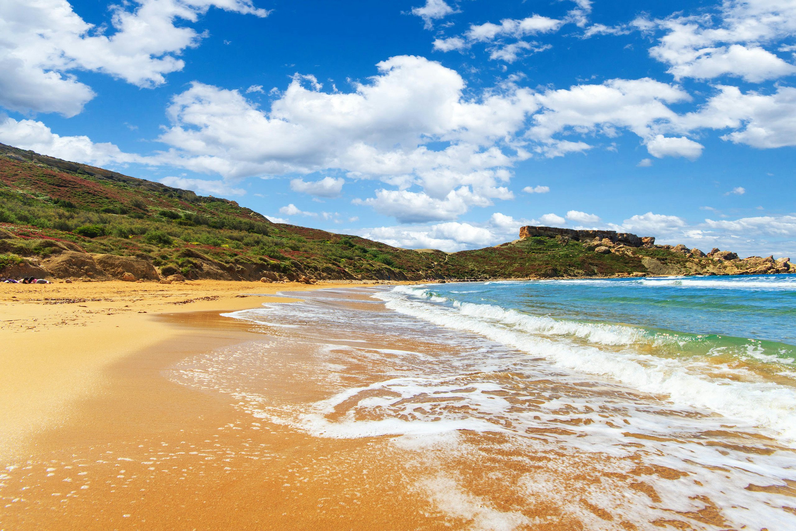 Golden Bay's sandy beach and gentle waves, a prime spot for beachside yacht charters in Malta.